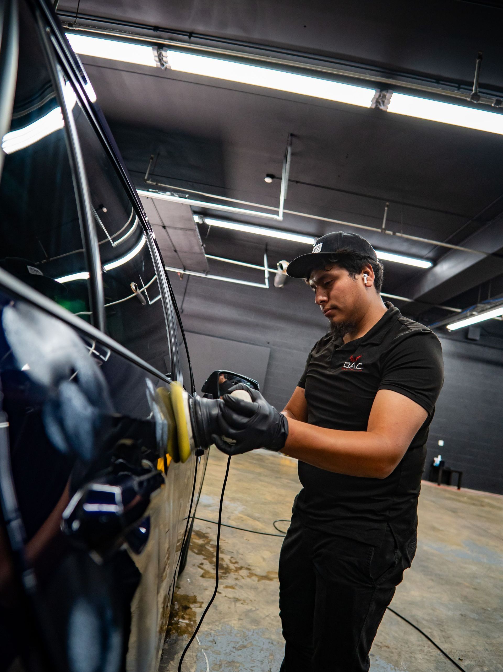 A man is polishing the hood of a yellow sports car.