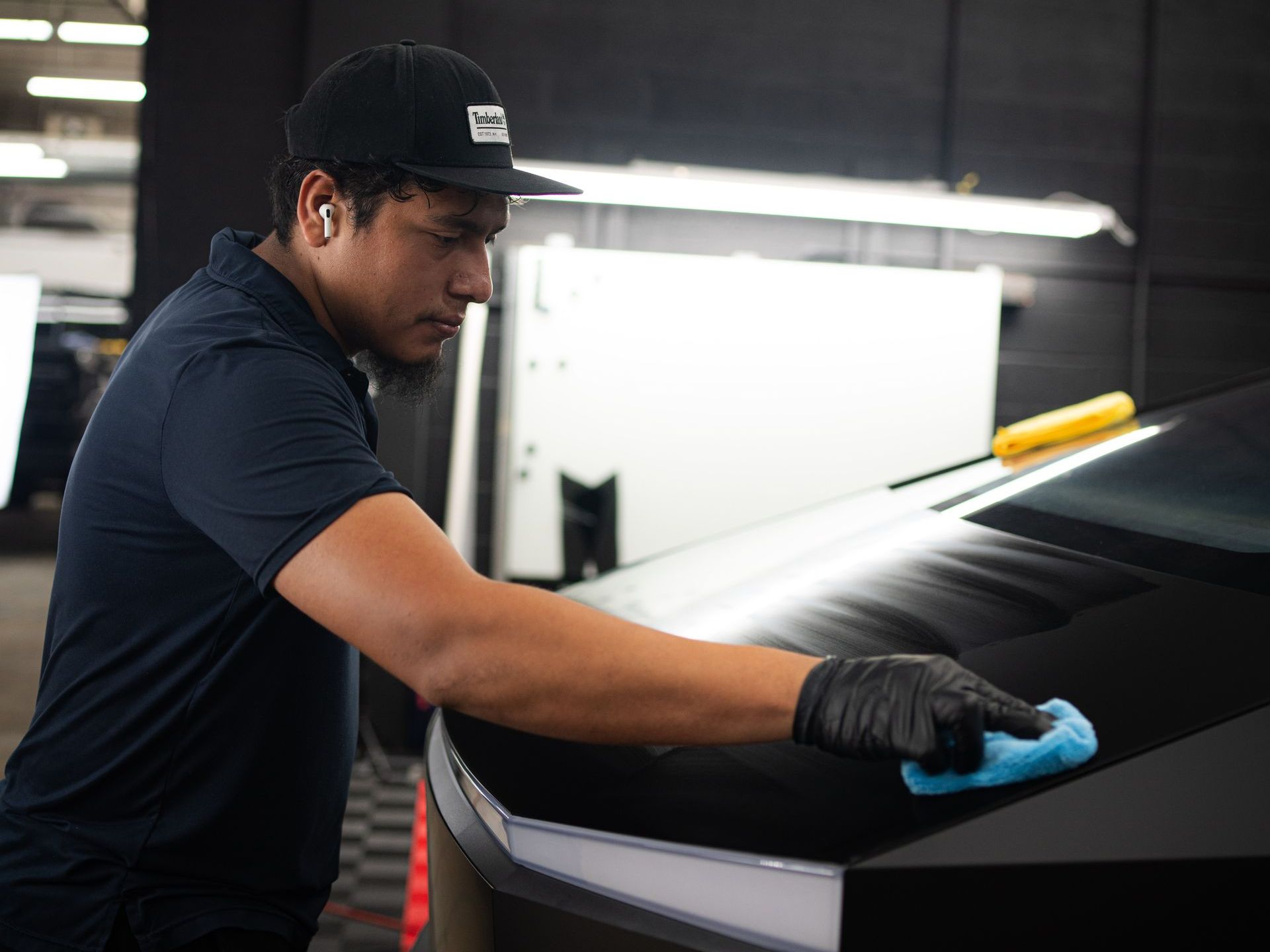 A person wearing black gloves is cleaning a car with a brush.