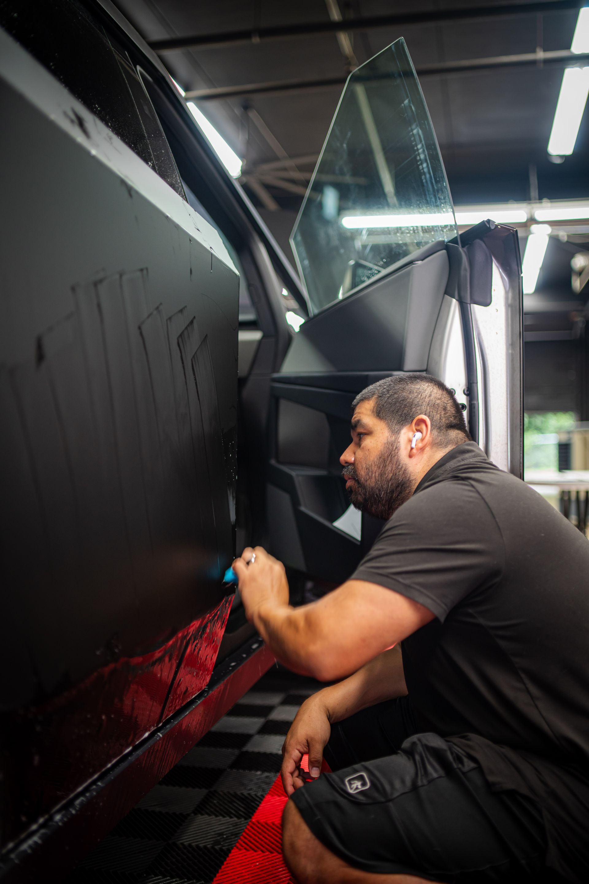 A man in a black shirt is giving a thumbs up in front of a truck.