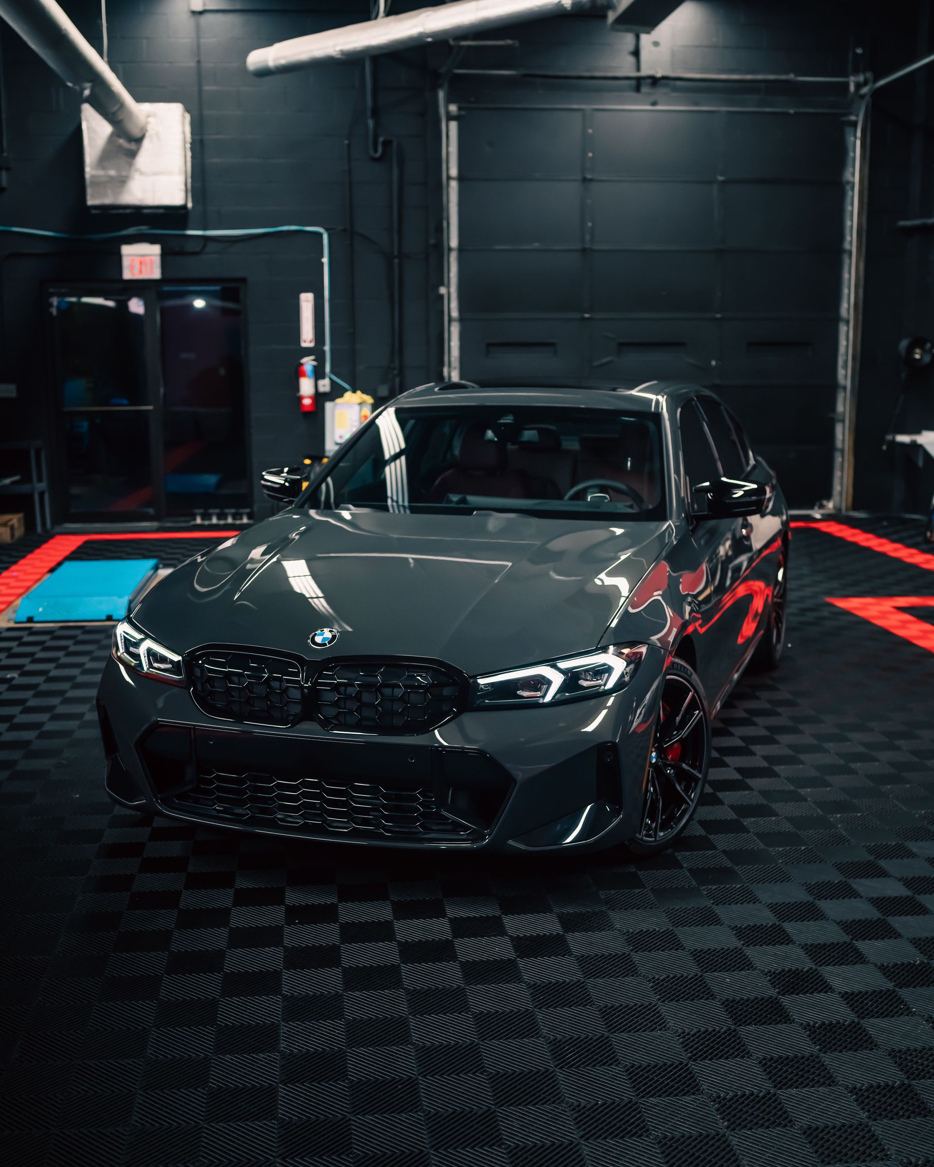 A bmw m3 is parked in a garage with a checkered floor.