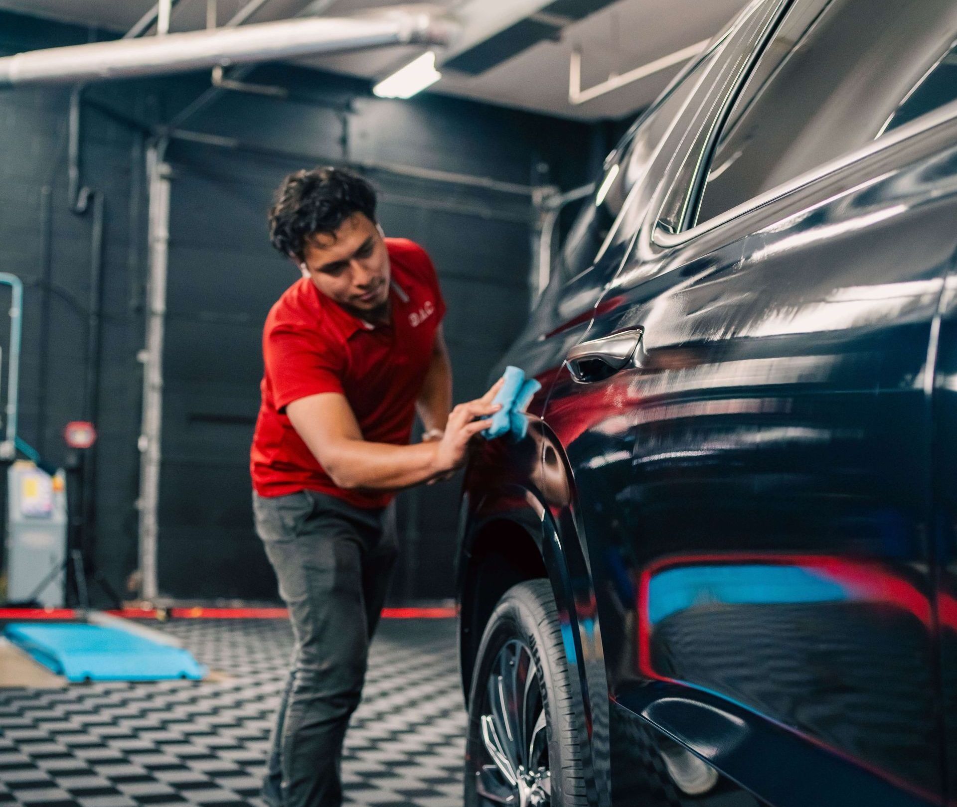 A person wearing black gloves is cleaning a car with a brush.