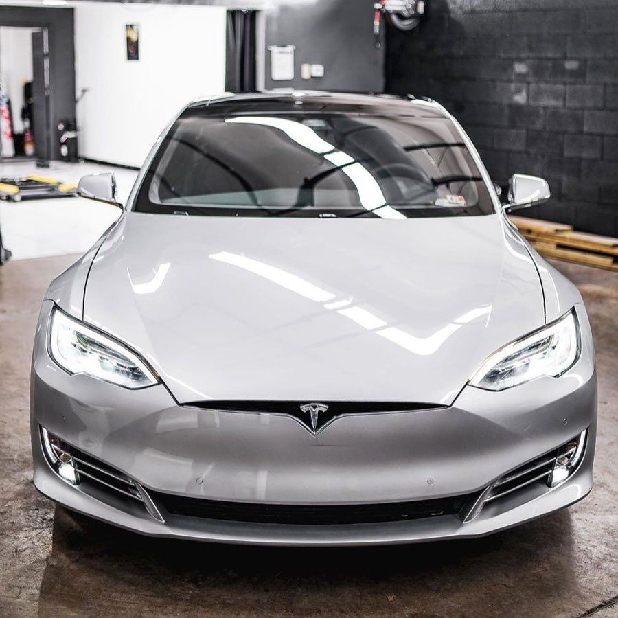 A silver tesla model s is parked in a garage.