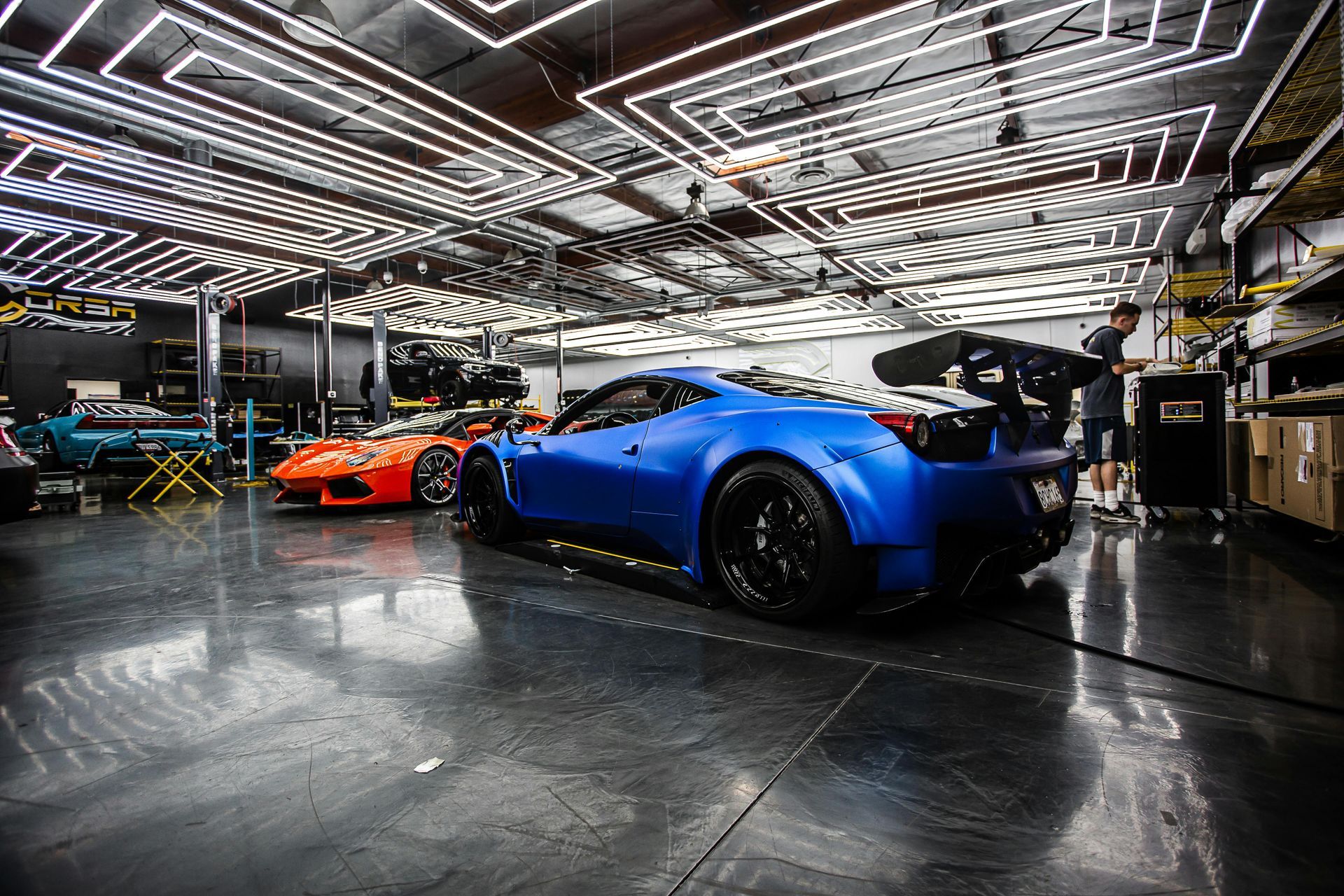 A blue car is parked in a garage next to a red car.