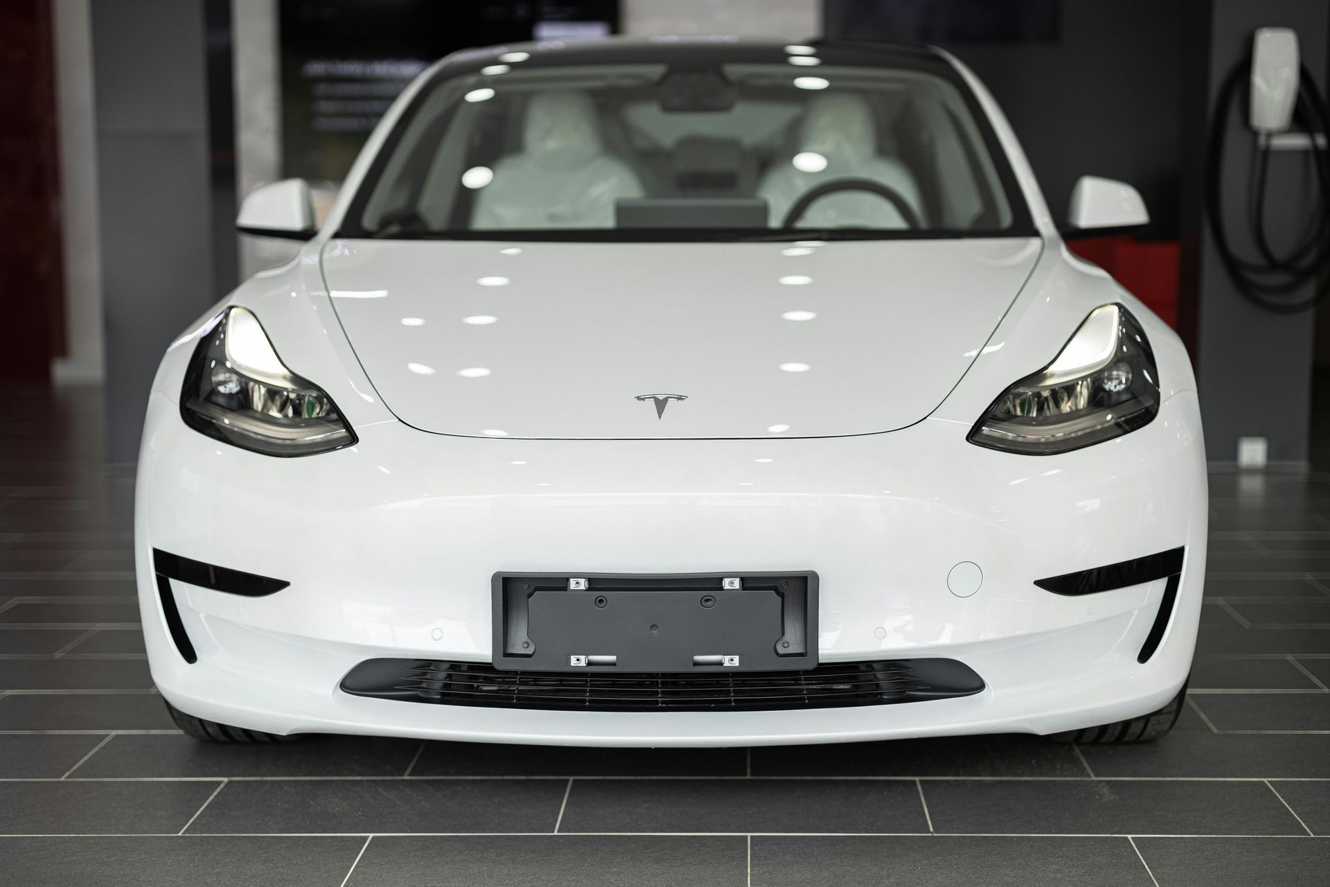 A white tesla model 3 is parked in a showroom.