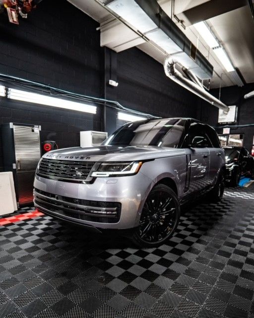 A silver range rover is parked in a garage with a checkered floor.