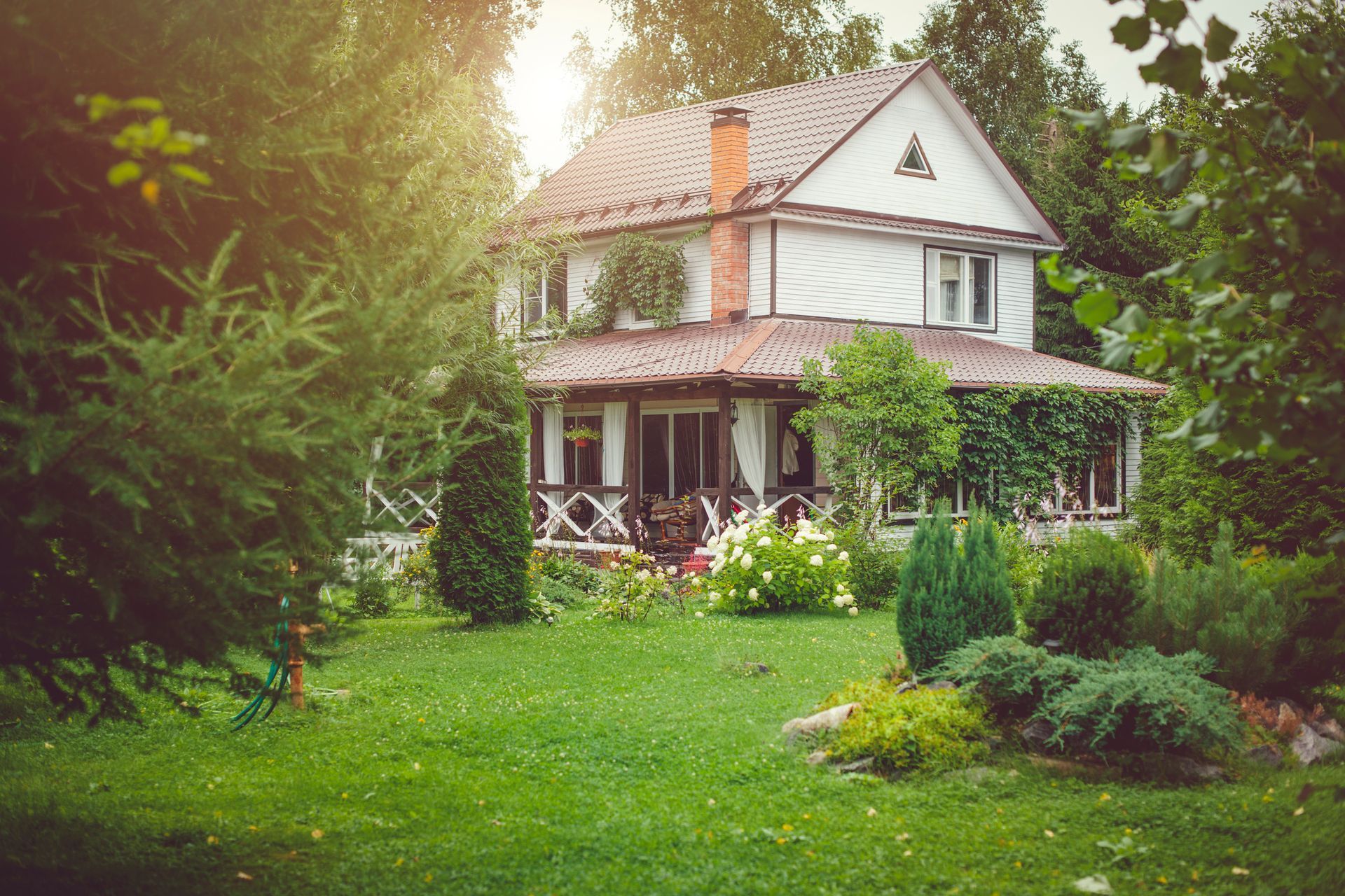 A large house with a large lawn in front of it surrounded by trees.