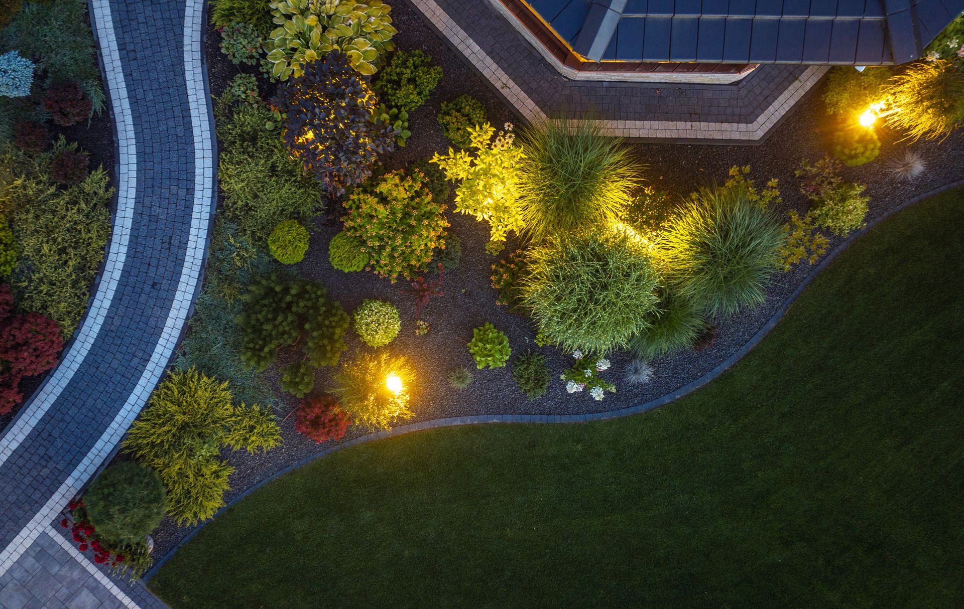 An aerial view of a garden with a house in the background at night.