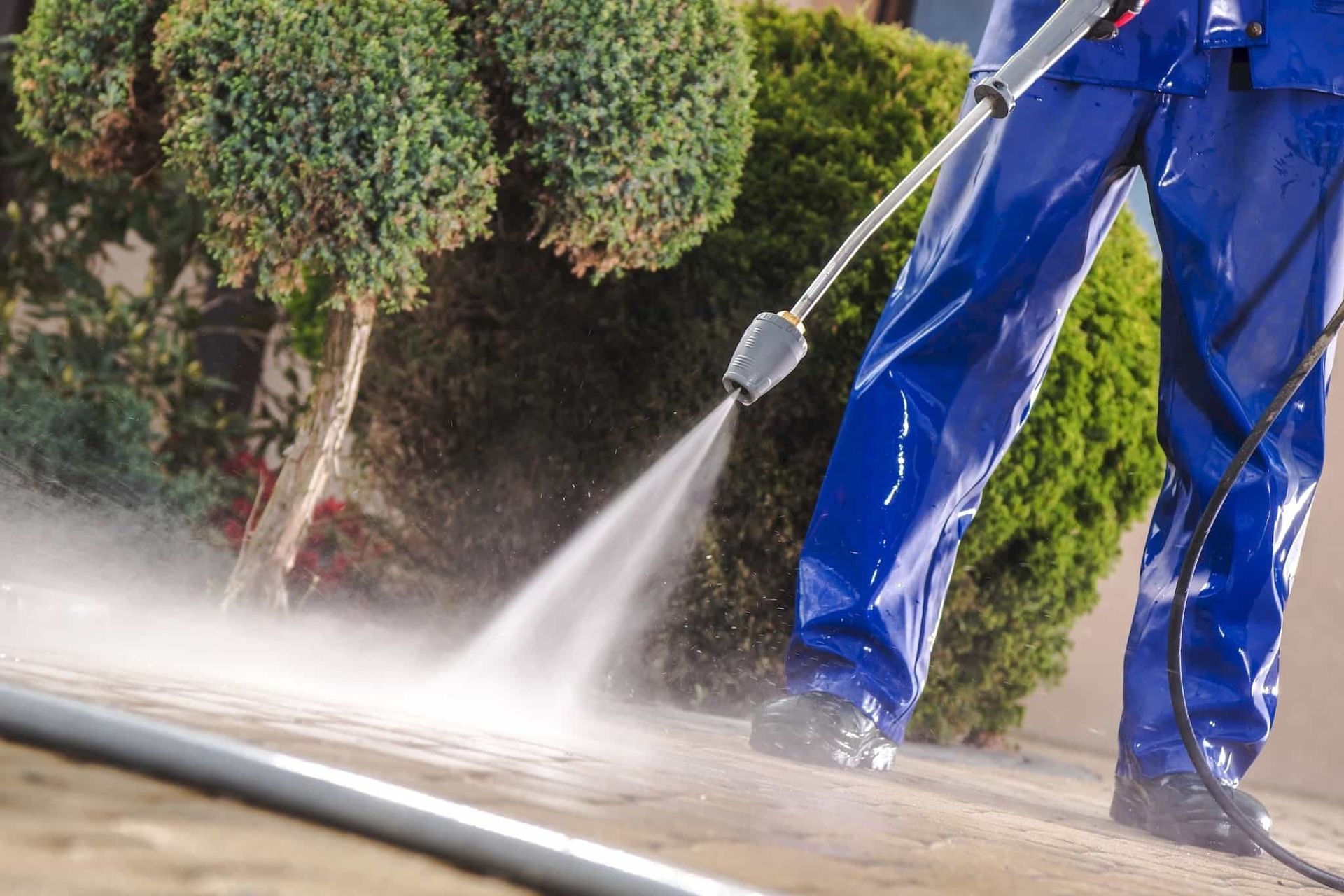 Worker using a leaf blower to clear autumn leaves in the park.