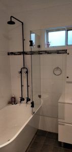 A Bathroom With a Bathtub, Shower, Sink and Mirror — Superior Windows & Doors Taree, NSW