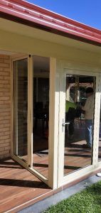 A Man is Standing Outside of a House With a Sliding Glass Door — Superior Windows & Doors Taree, NSW