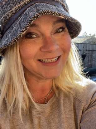 A woman is wearing a hat and smiling for the camera.