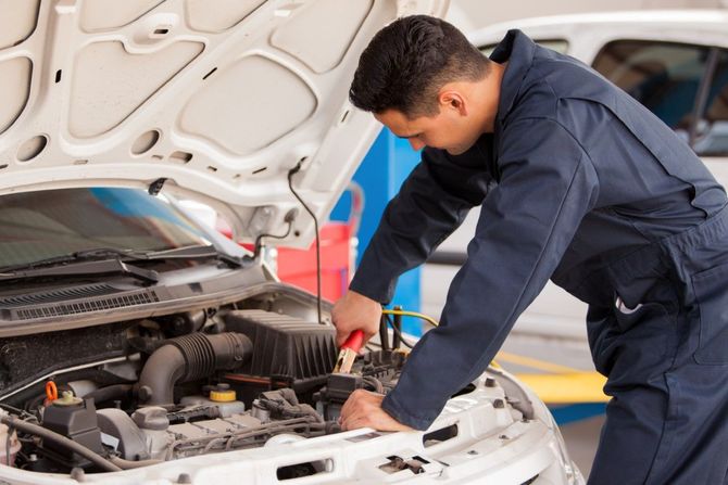 Mechanic inspecting a car engine with the hood open in a garage