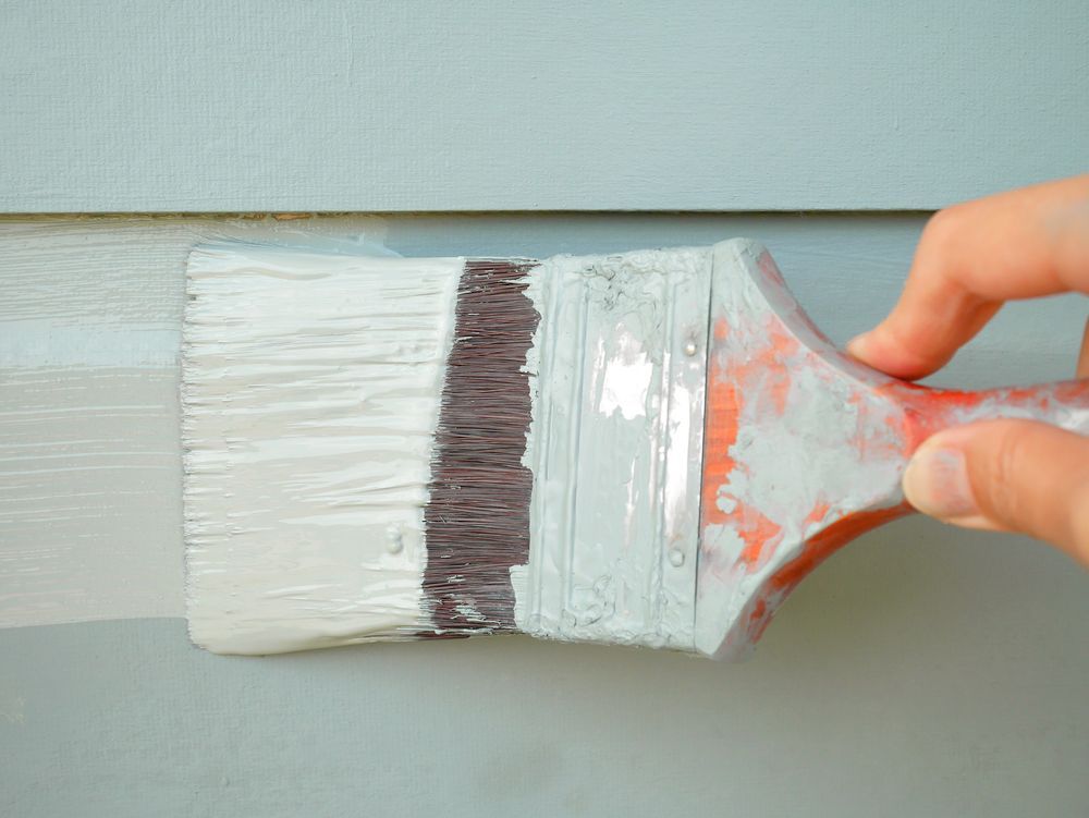 image of a paint brush painting the outside of a house