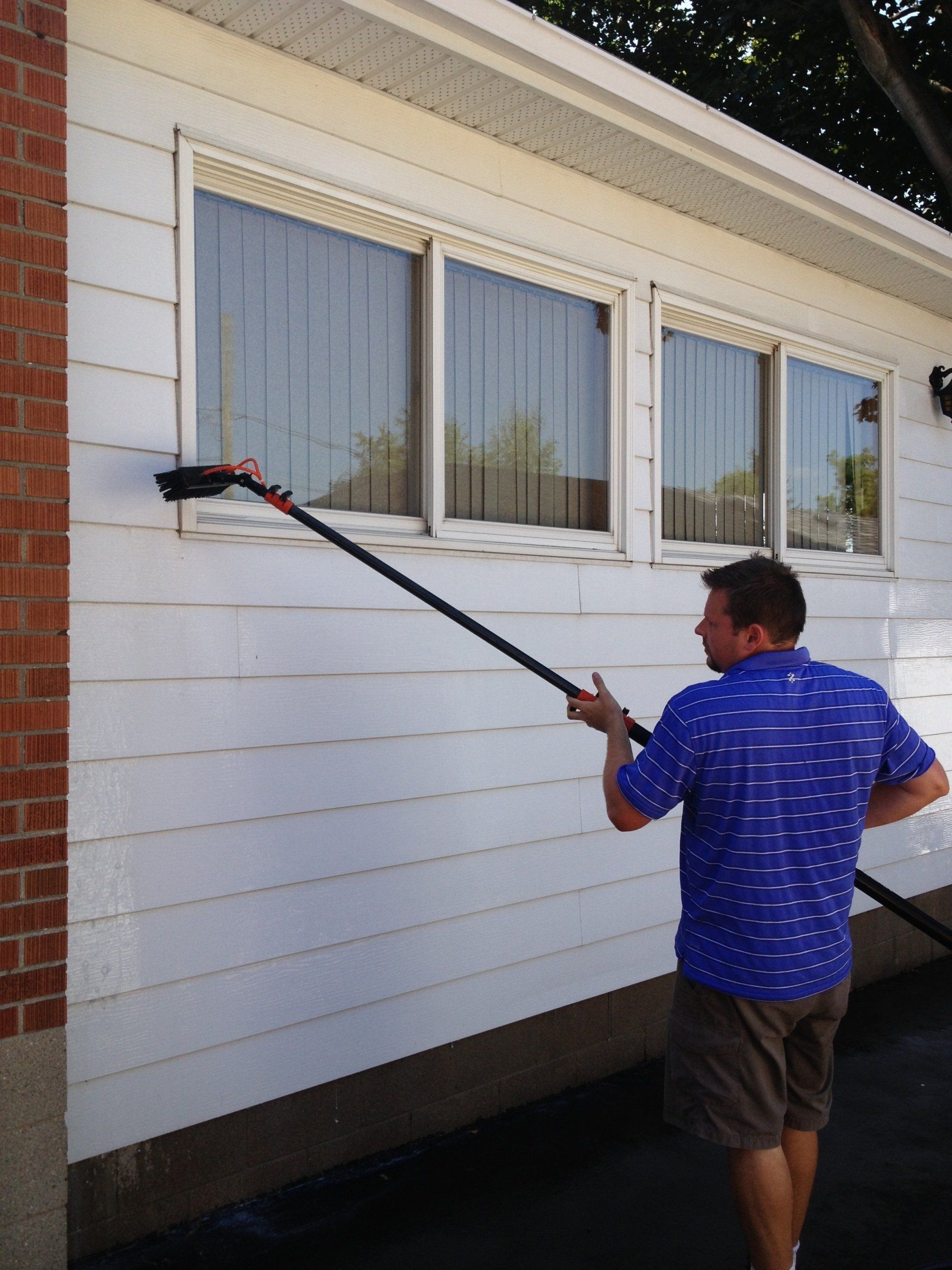 picture of a man washing vinyl siding on a house