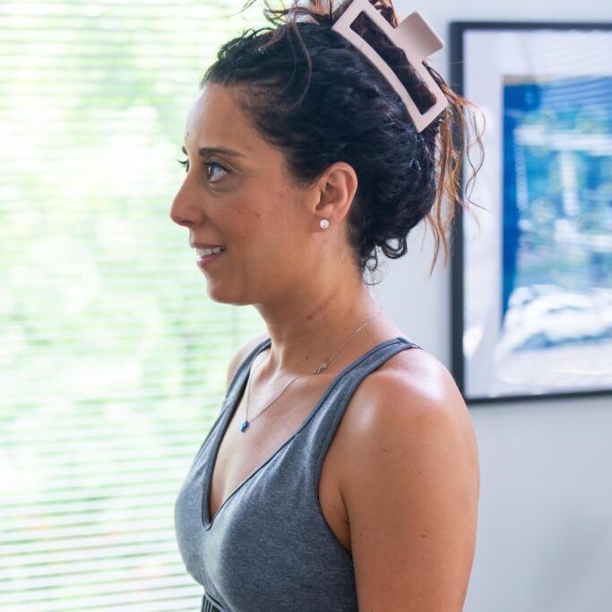 A woman with a hair clip in her hair is standing in front of a window