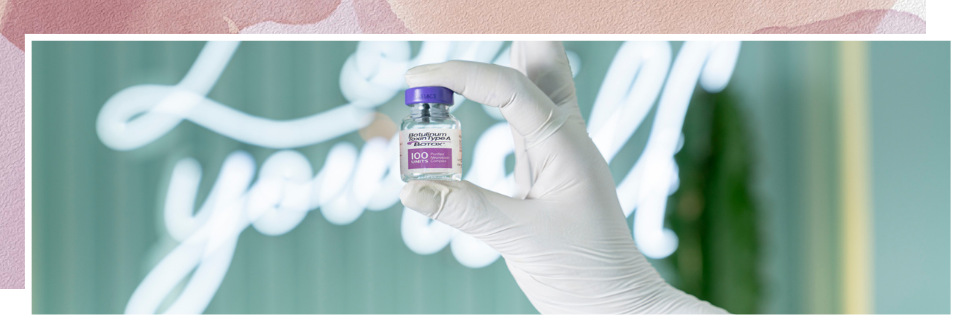 A person is holding a bottle of botox in their gloved hand.