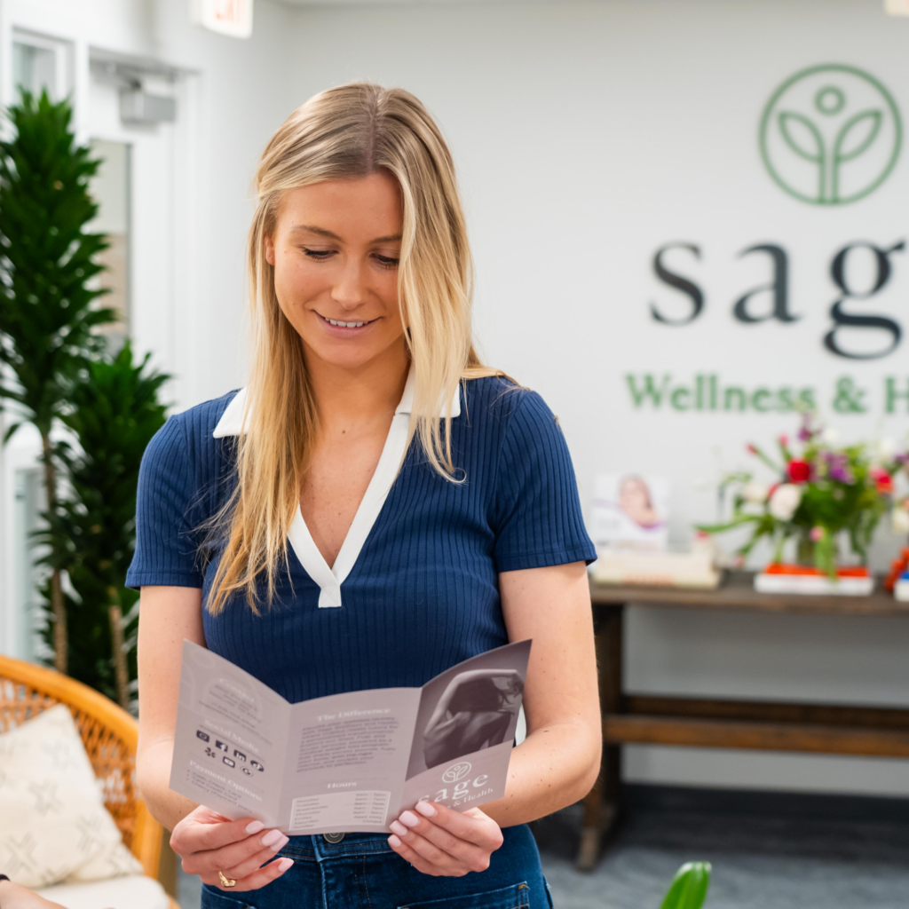 A woman is reading a pamphlet in front of a sign that says sag wellness & health