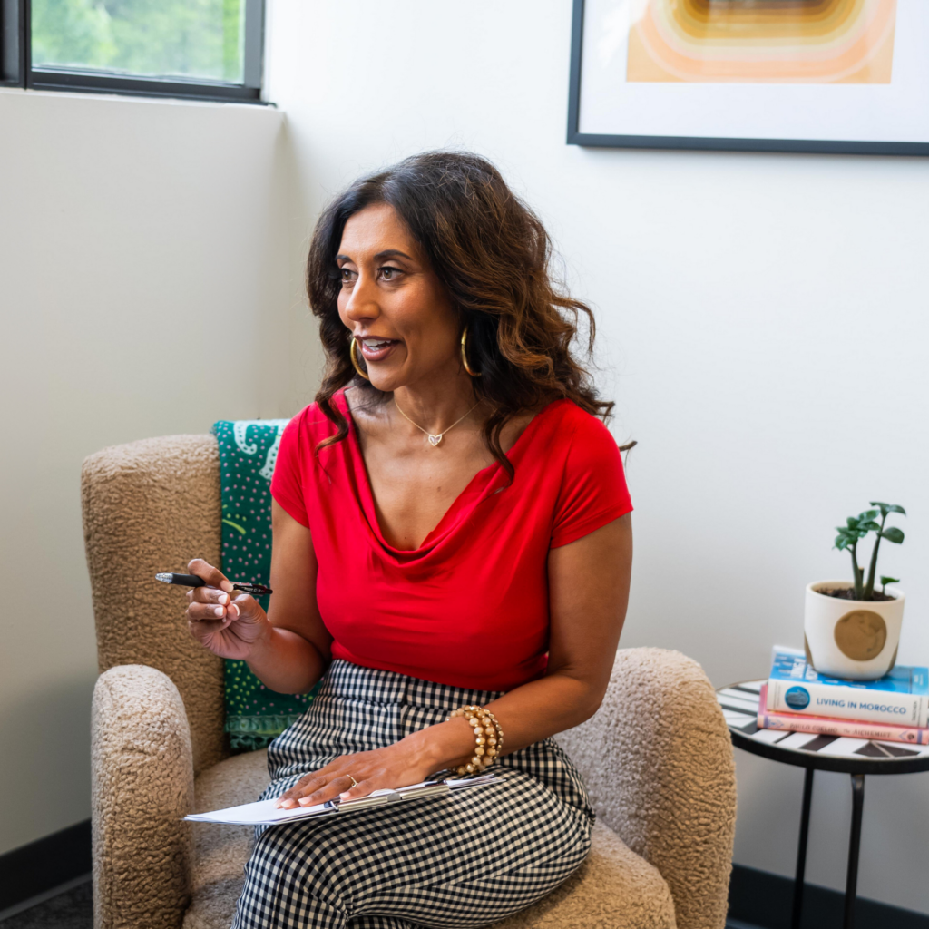 A woman is sitting in a chair with a pen in her hand.