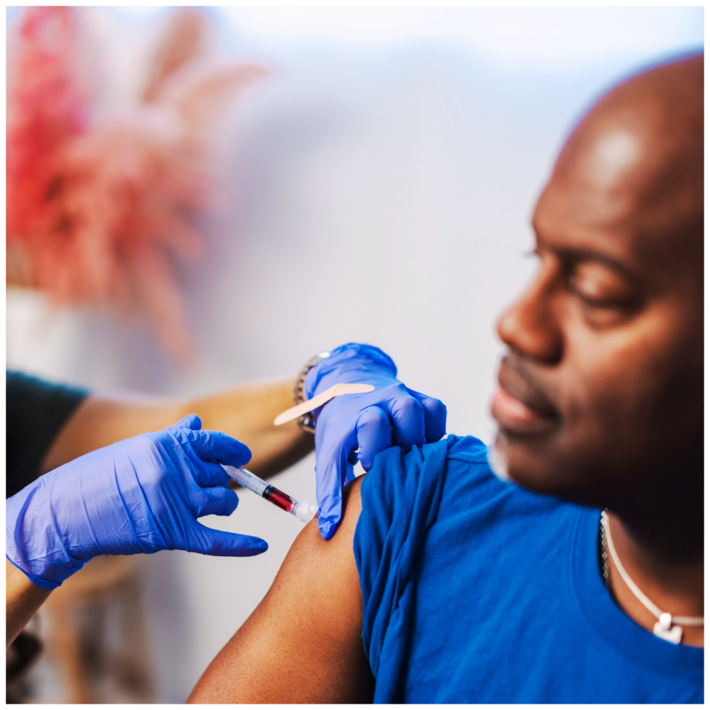 A man in a blue shirt is getting a vaccine in his arm