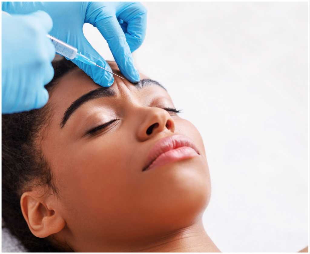 A woman is getting a botox injection in her forehead.