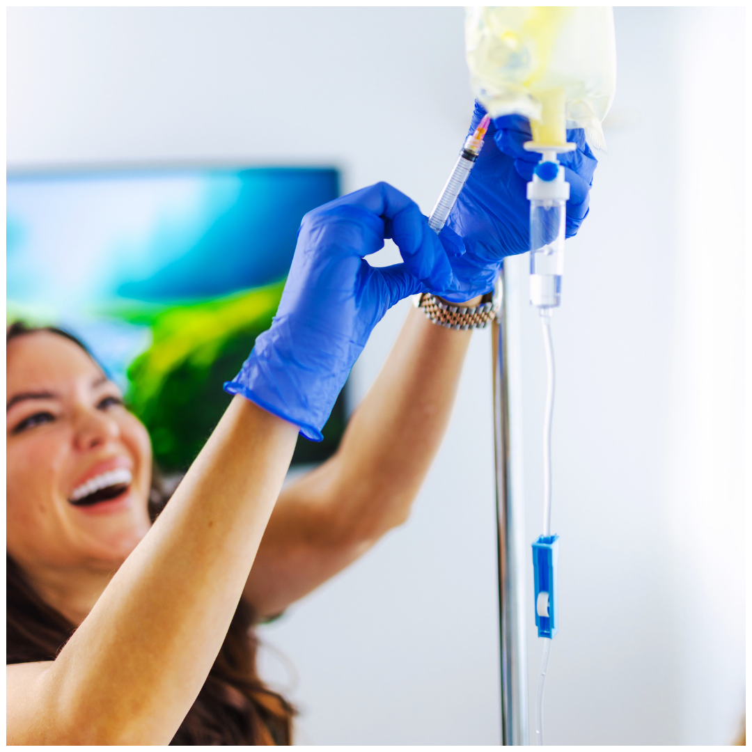 A woman wearing blue gloves is holding an iv bag.