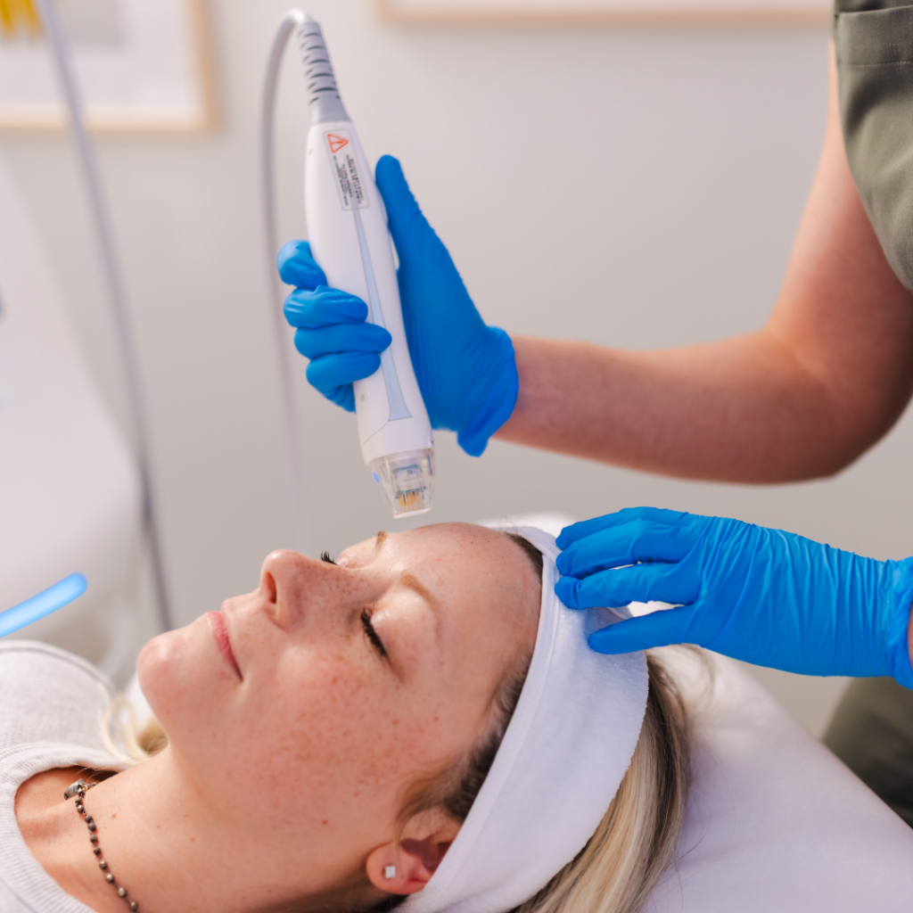 A woman is getting a facial treatment from a person wearing blue gloves