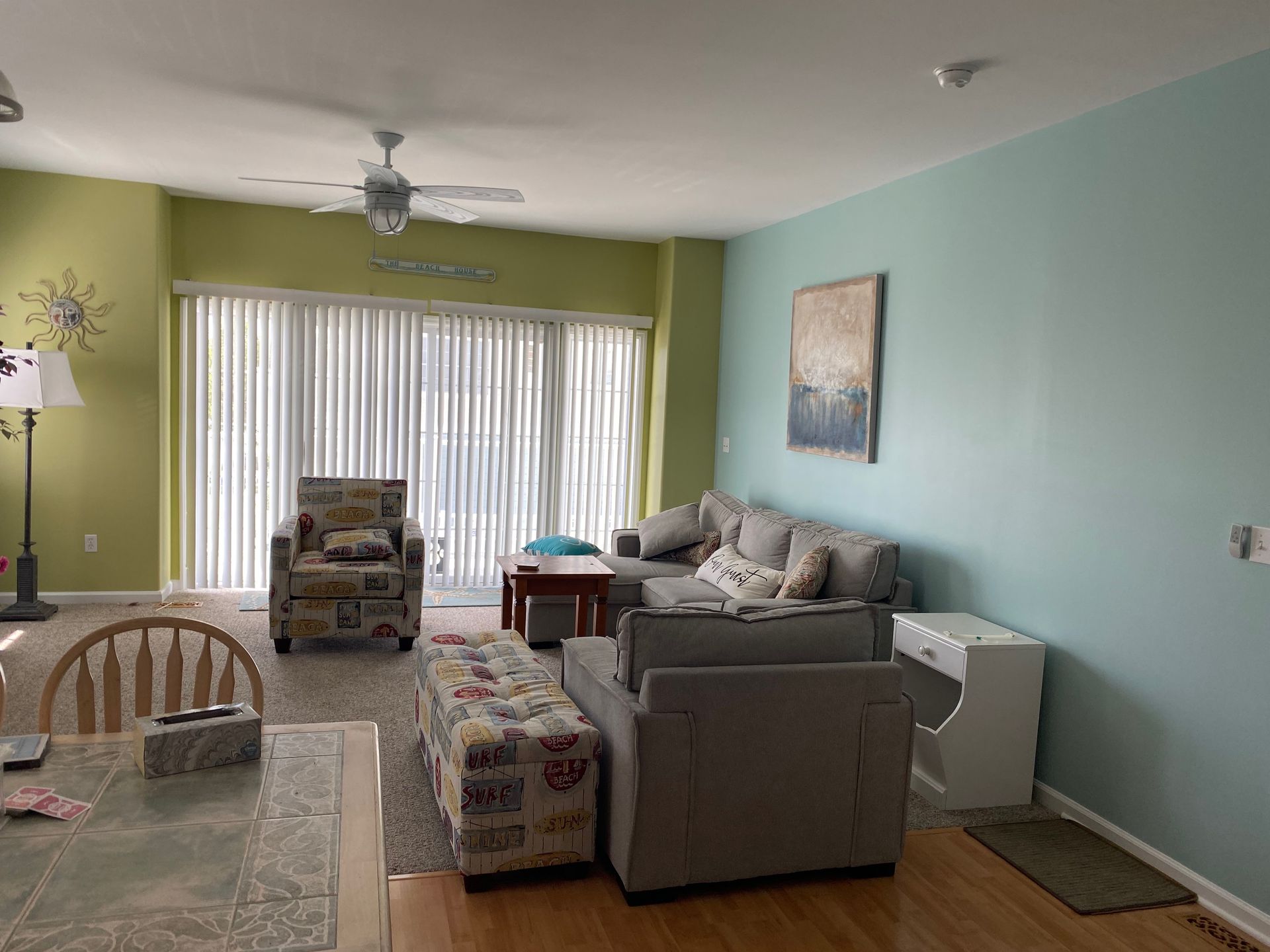 A living room with a couch , chair , table and ceiling fan.