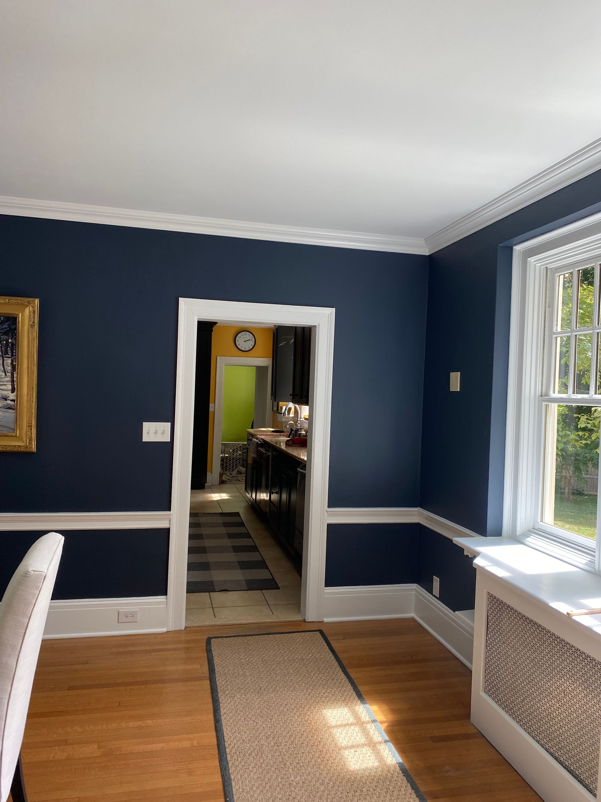 A dining room with dark blue walls and white trim.