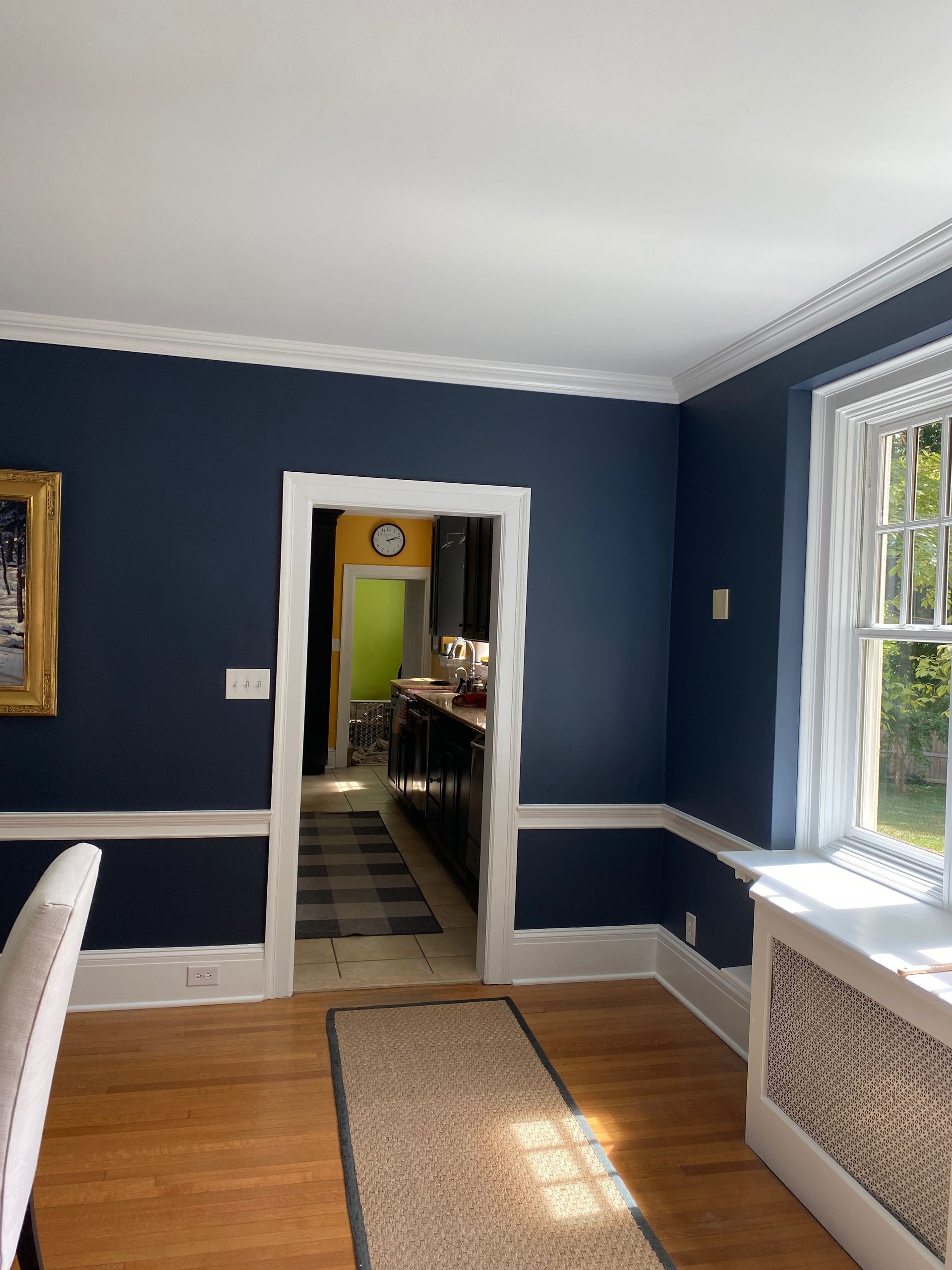 A dining room with dark blue walls and white trim