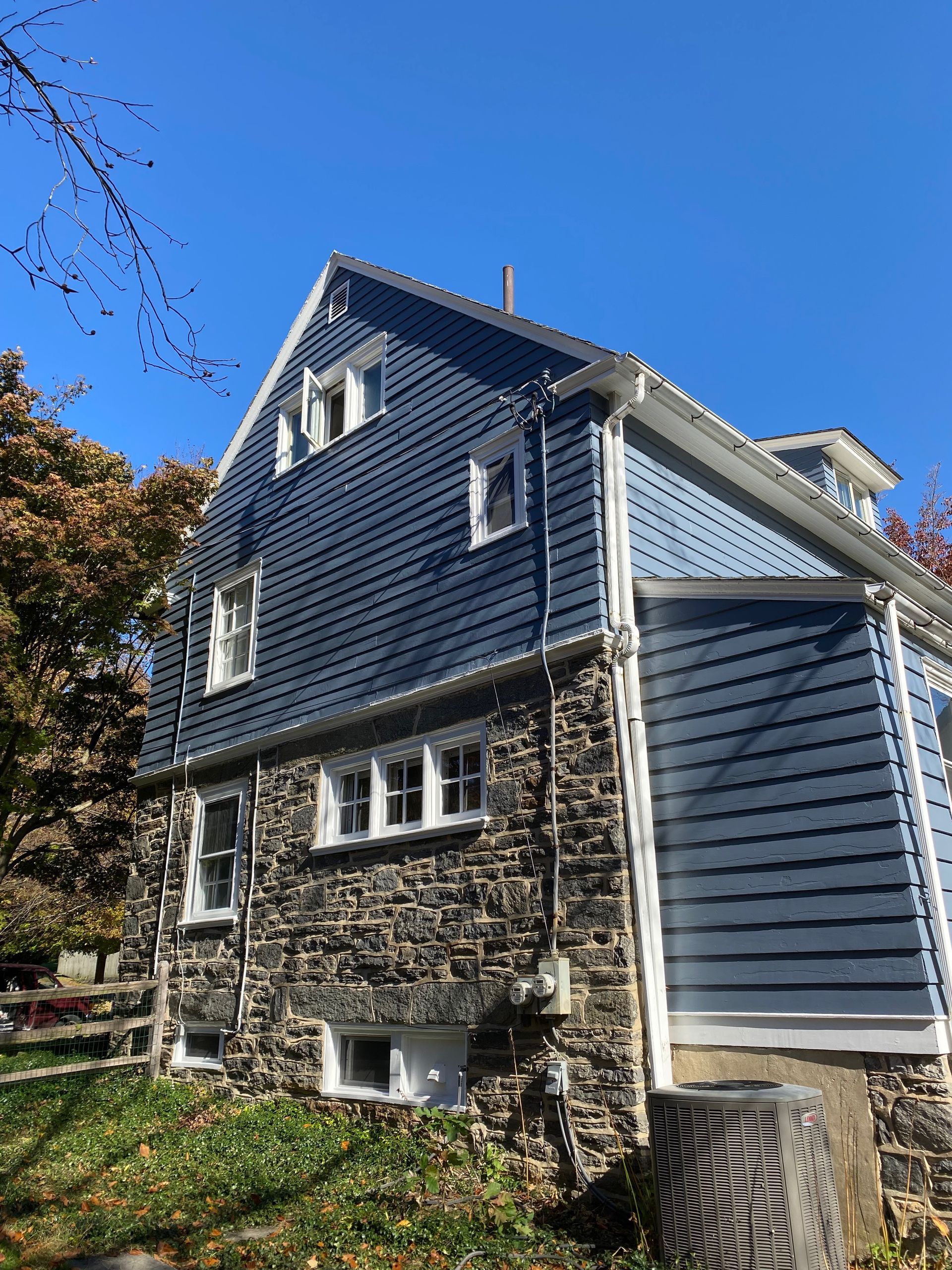 A large house with a blue siding and a stone wall.