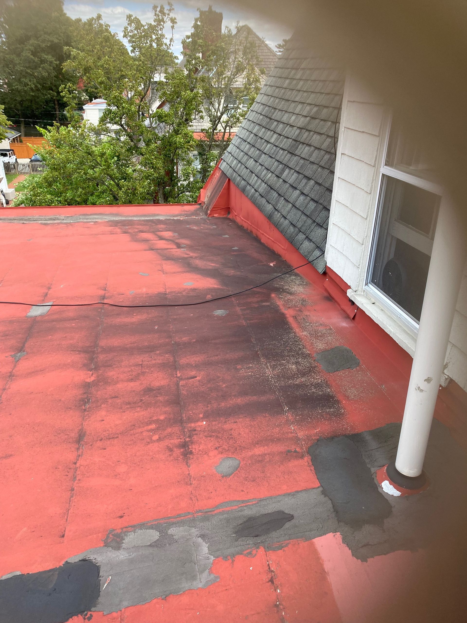A red roof with a window on the side of a house.
