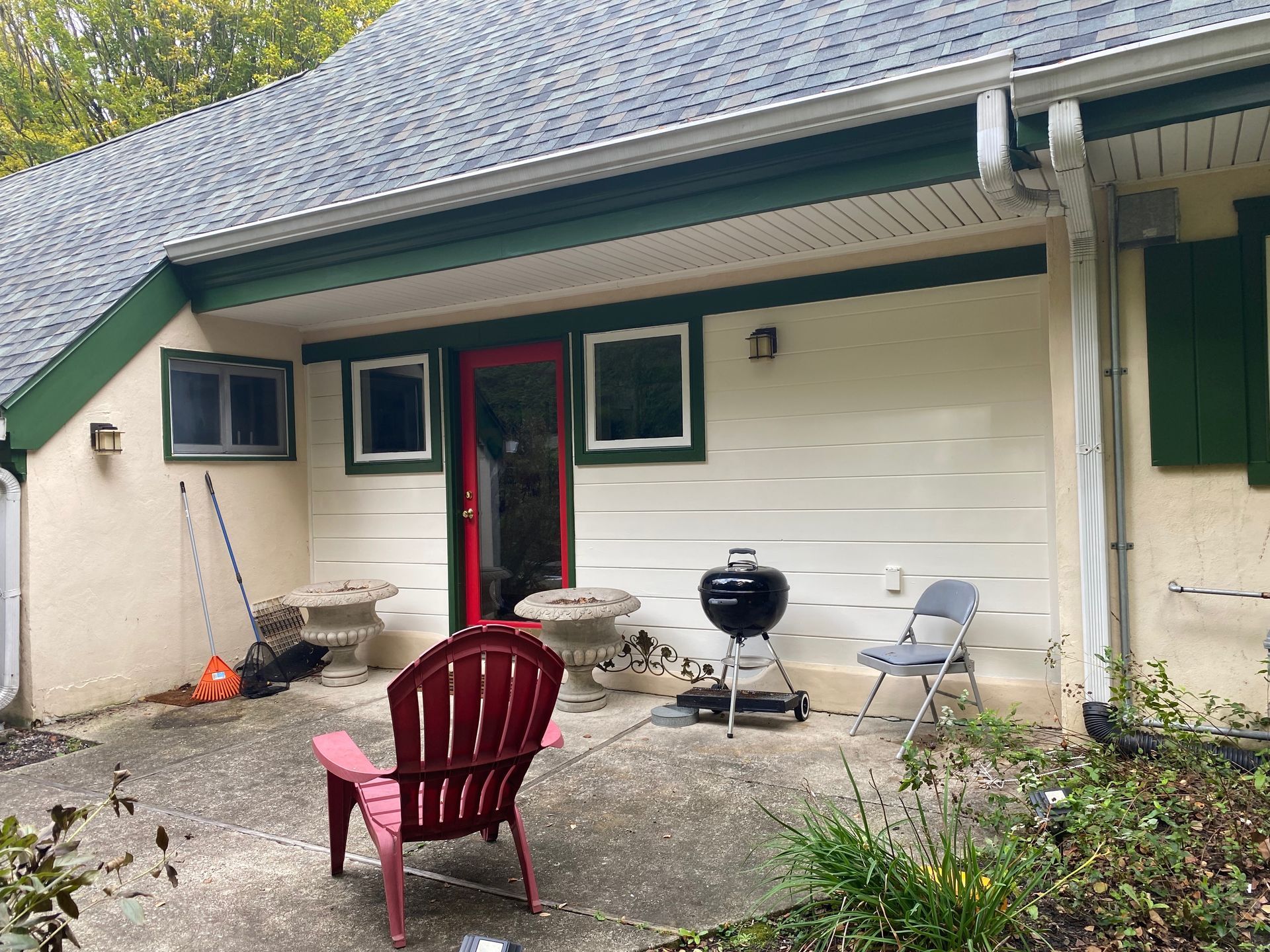 A red chair is sitting on a patio in front of a house.