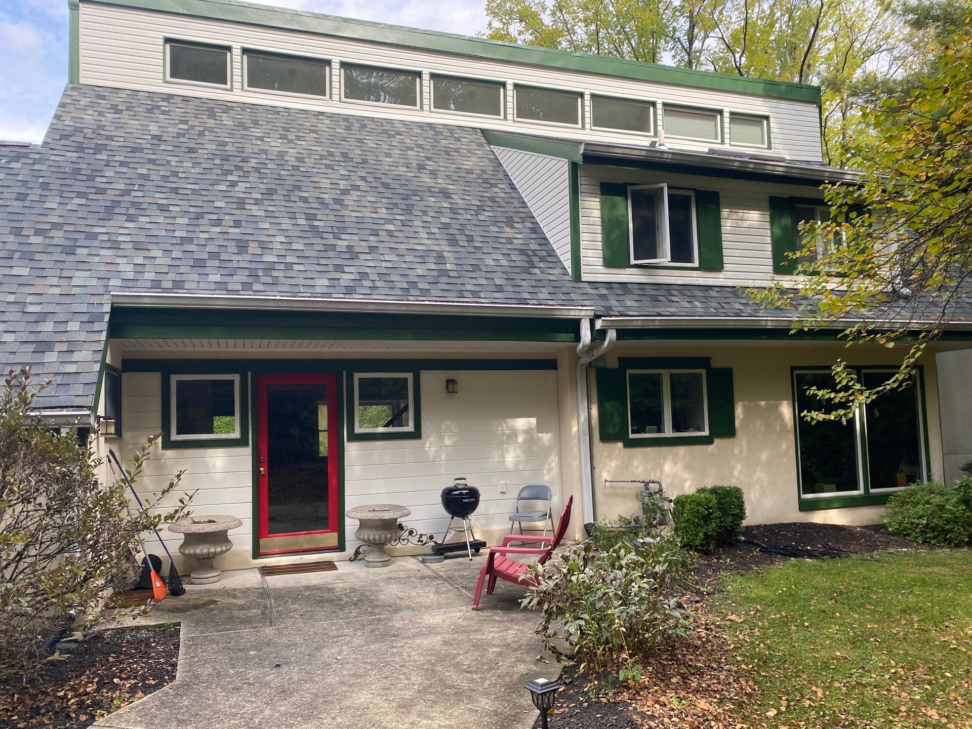 A white house with a gray roof and green shutters