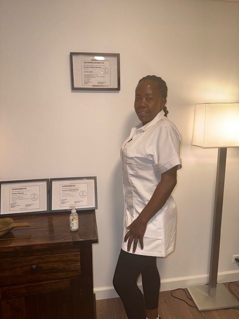 Hænder giver rygmassage i svagt oplyste omgivelser. Personen, der modtager massagen, ligger på et håndklæde.