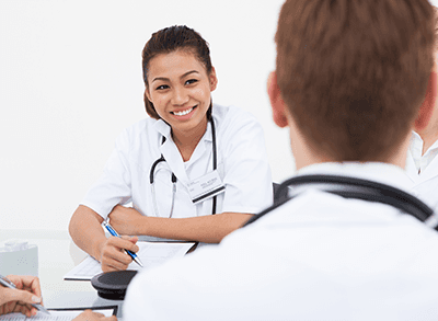 Smiling female doctor looking at colleague in meeting at hospital