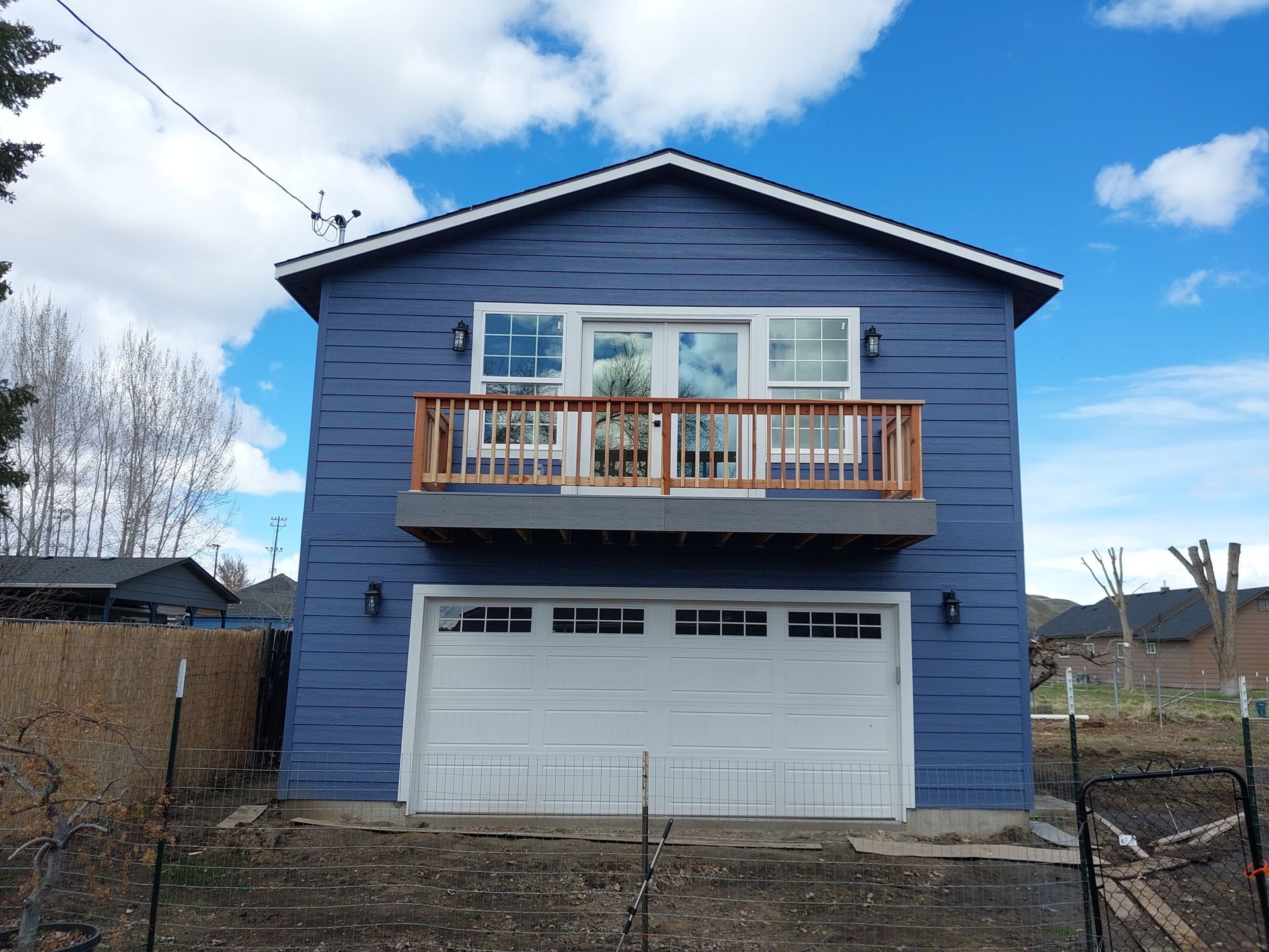 A blue house with a white garage door and a balcony