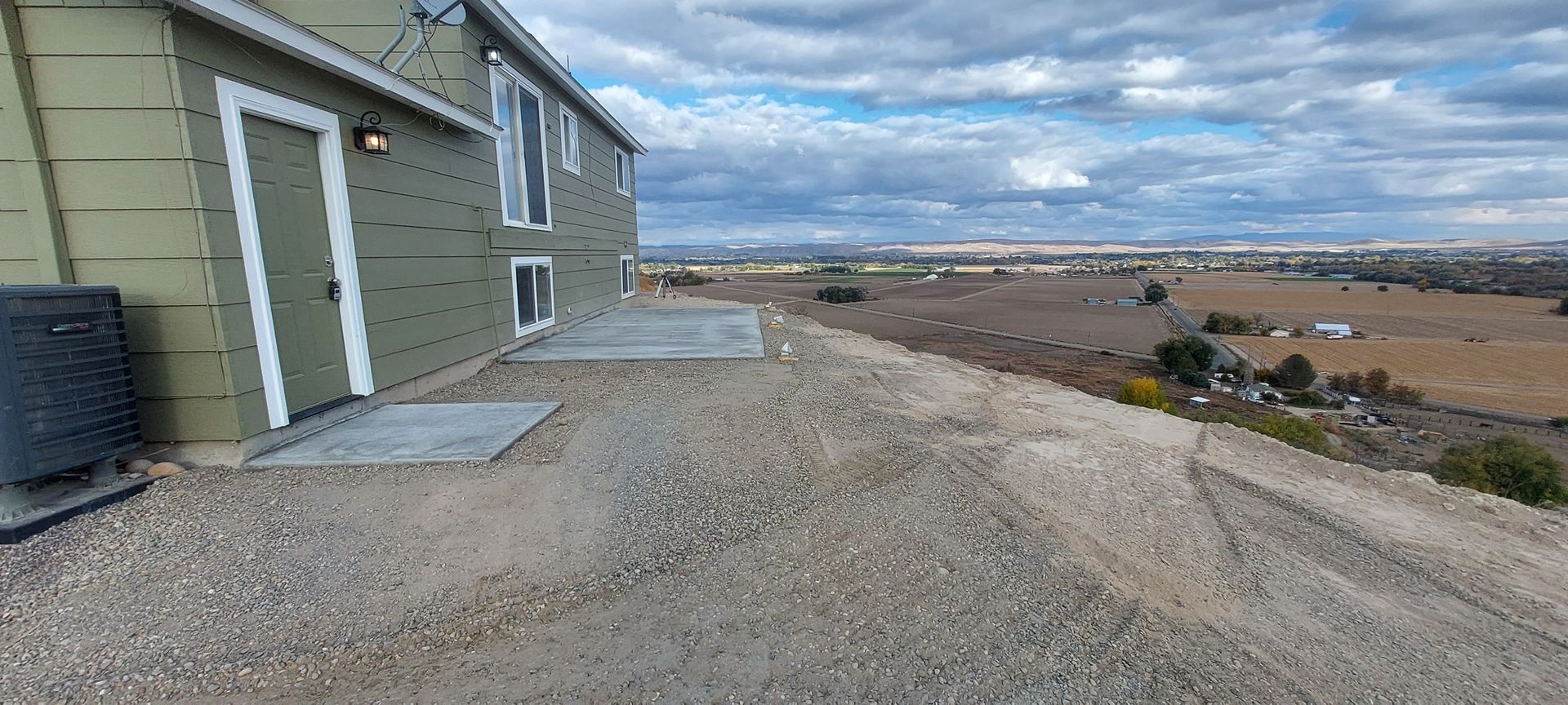 A house is sitting on top of a hill next to a dirt road.