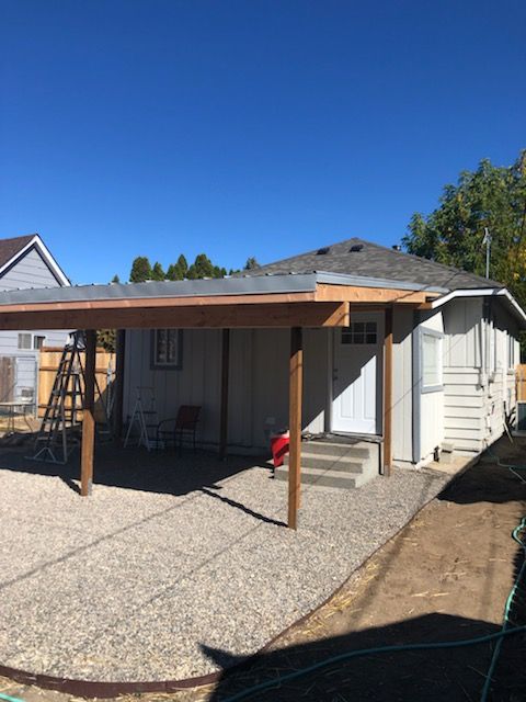 A house with a wooden porch and a gravel driveway
