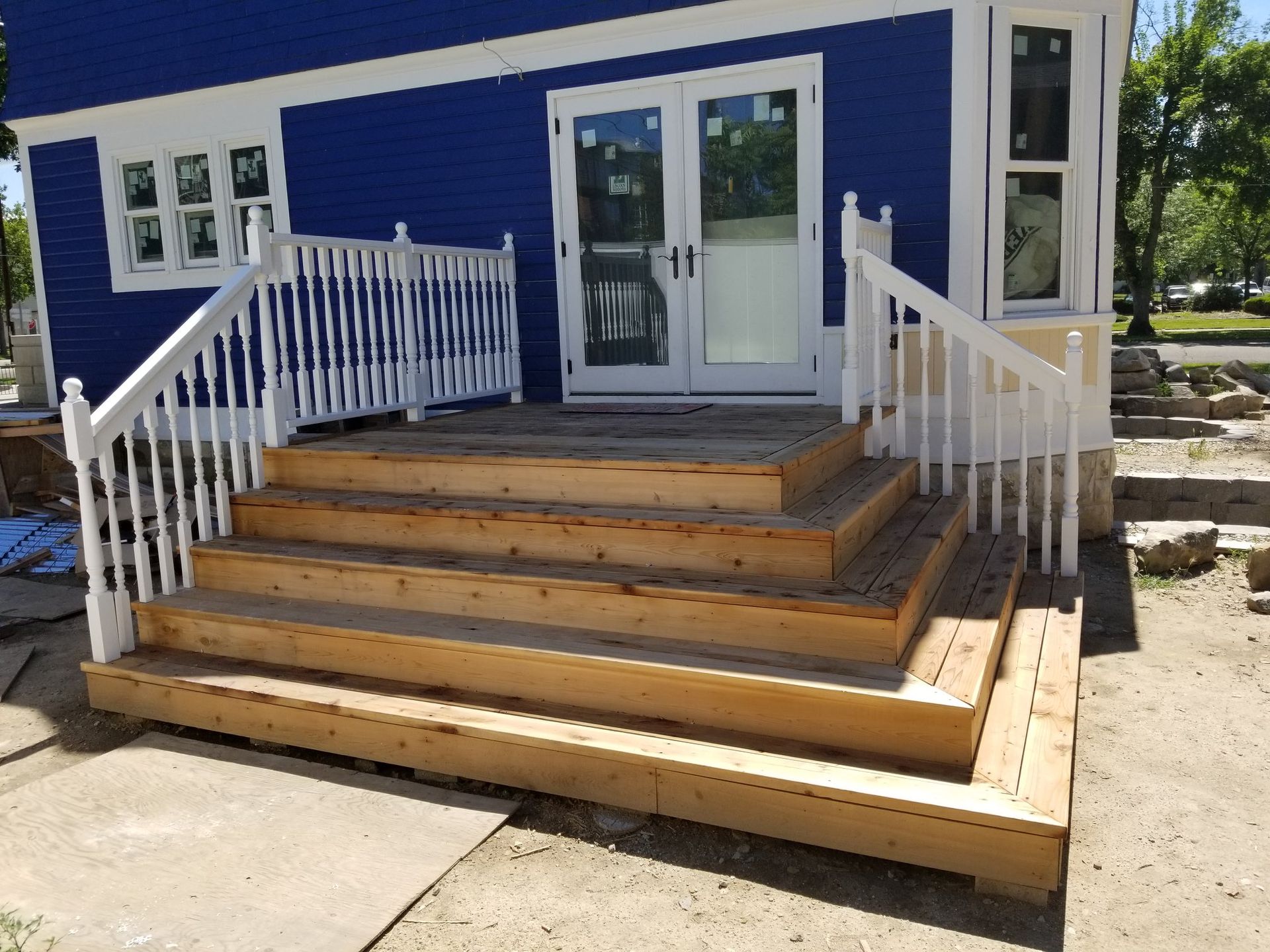 A blue house with a wooden deck and white railing