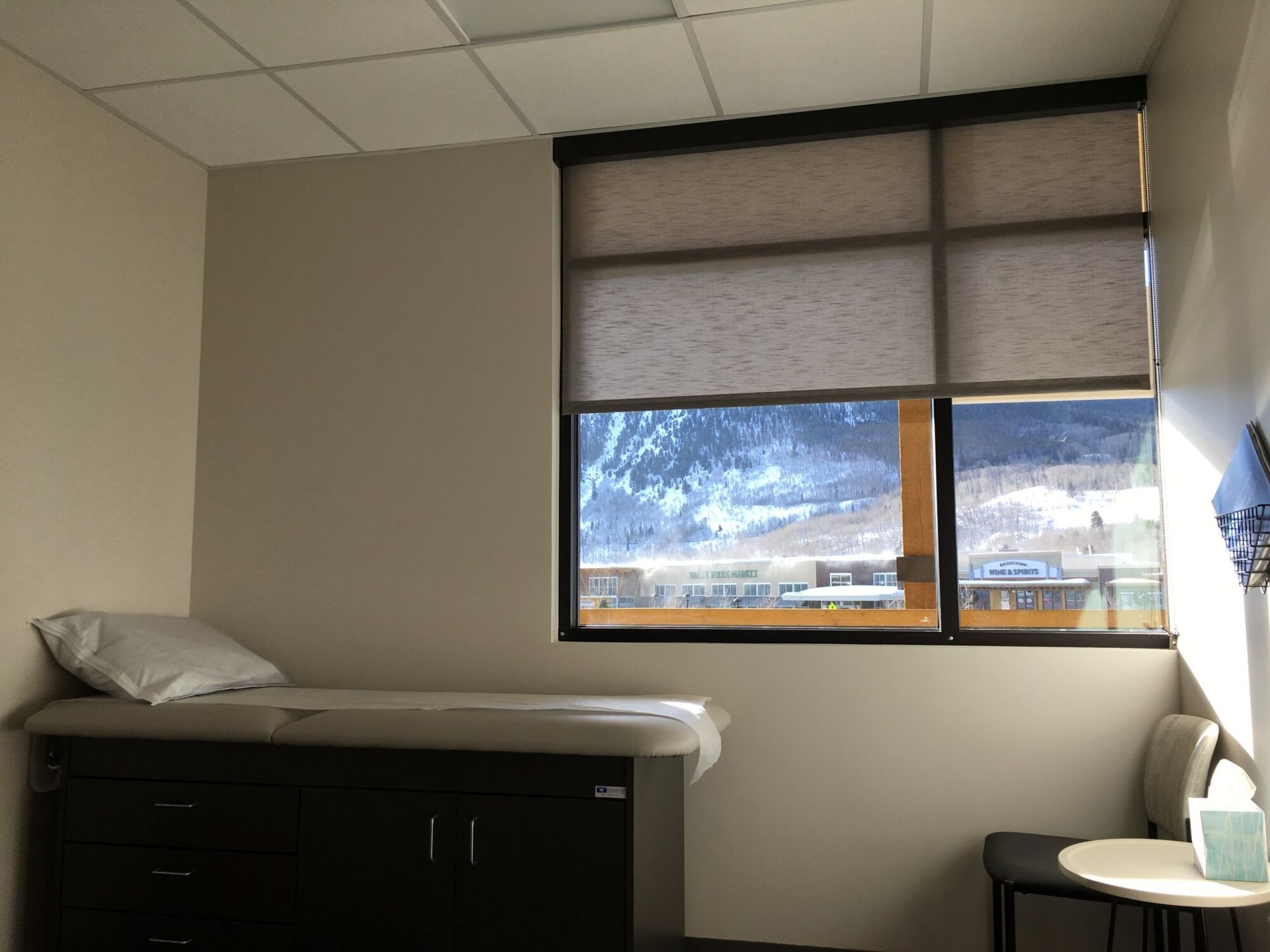 Exam room with bed, window, and chair. Exterior view of snow-covered landscape.