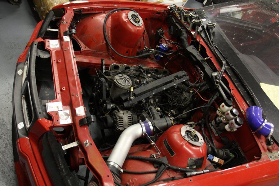 A red car with the hood open and the engine exposed