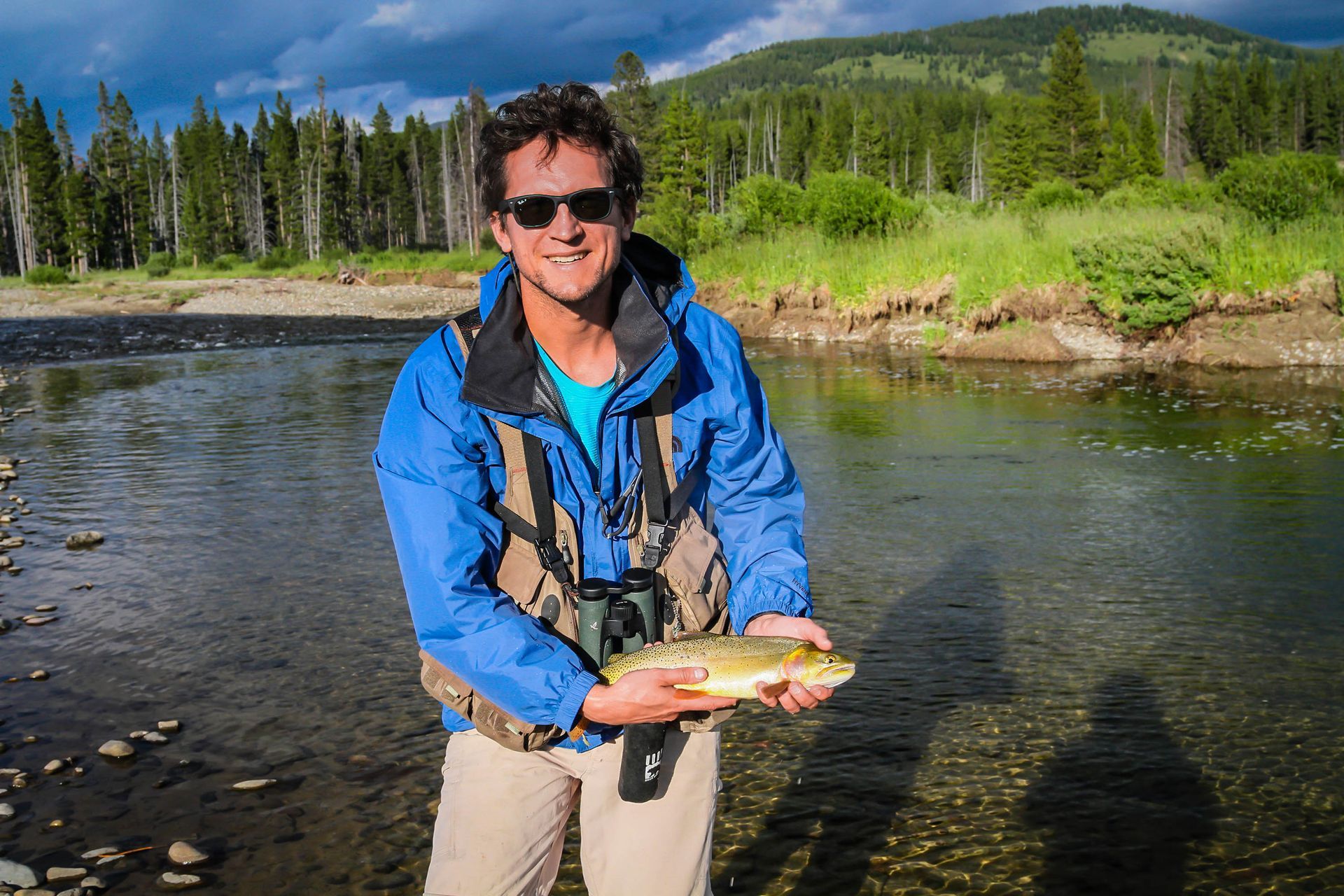 A fly fisherman proudly displays a Yellowstone Cutthroat Trout caught in the remote and wild Snake River.