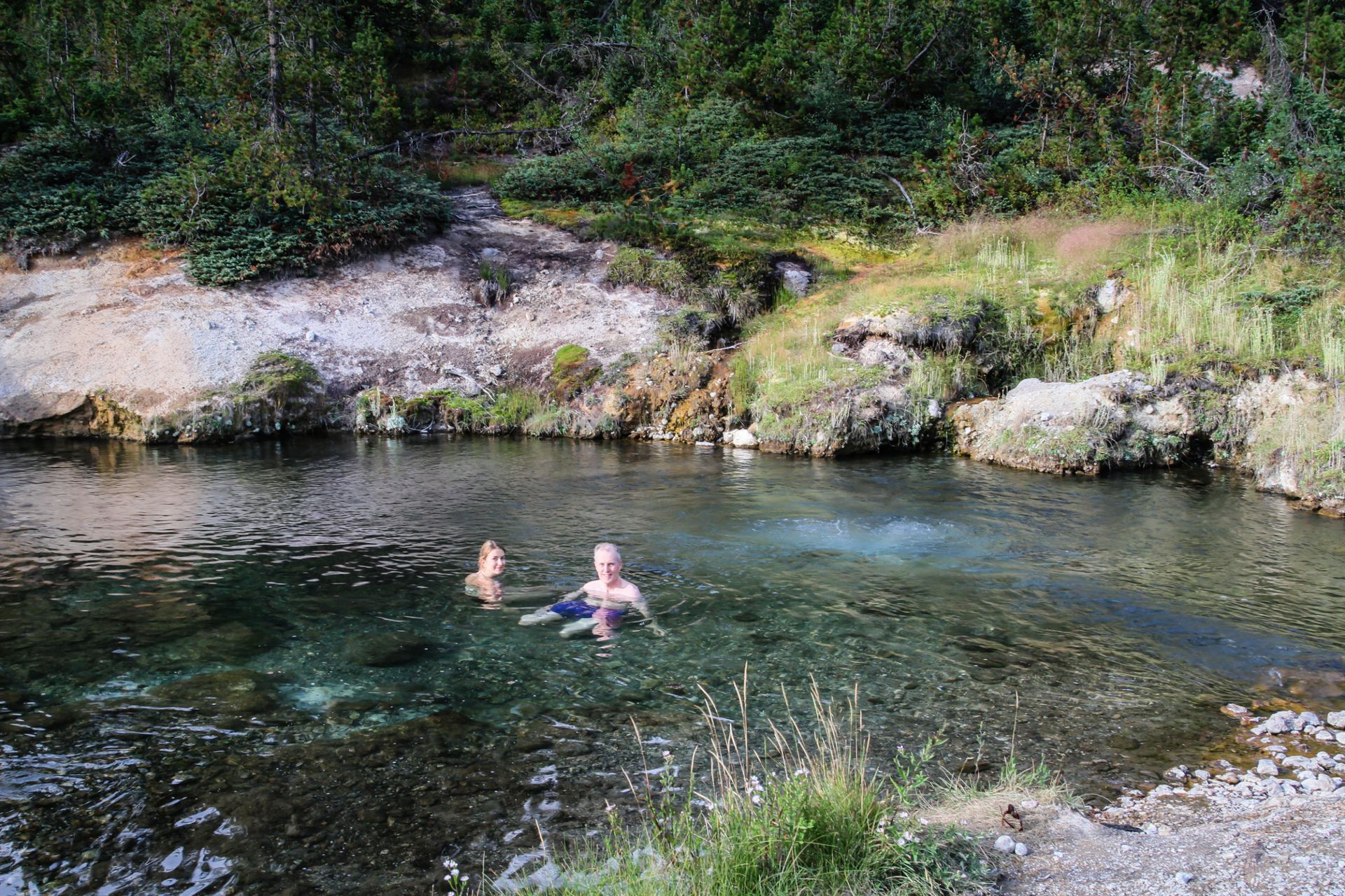 Hikers relax in the warm waters of the famous Mr. Bubbles hot spring in Yellowstone National Park.