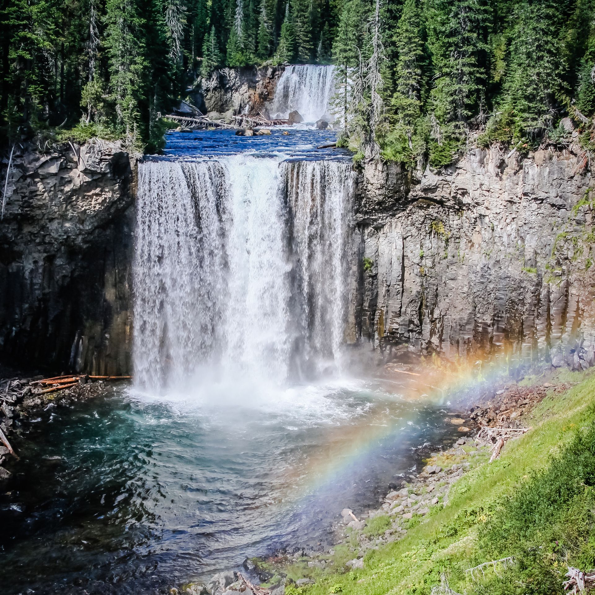 A small rainbow frames the view of Colonnade Falls, providing backpackers with a beautiful resting spot during a guided trek along the Bechler River Trail.