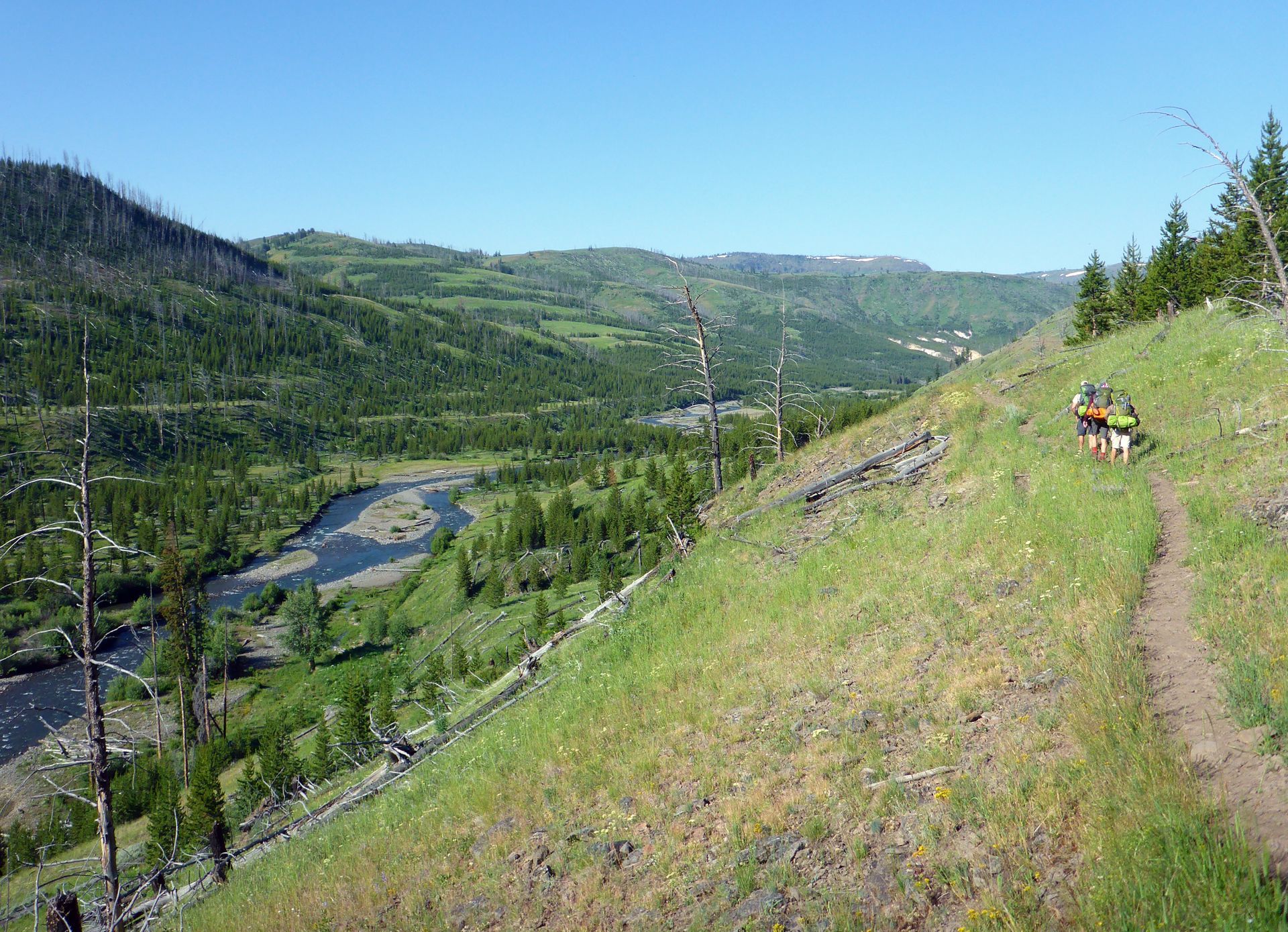 Backpackers enjoy the hike along the Cache Creek Trail under bright blue skies.