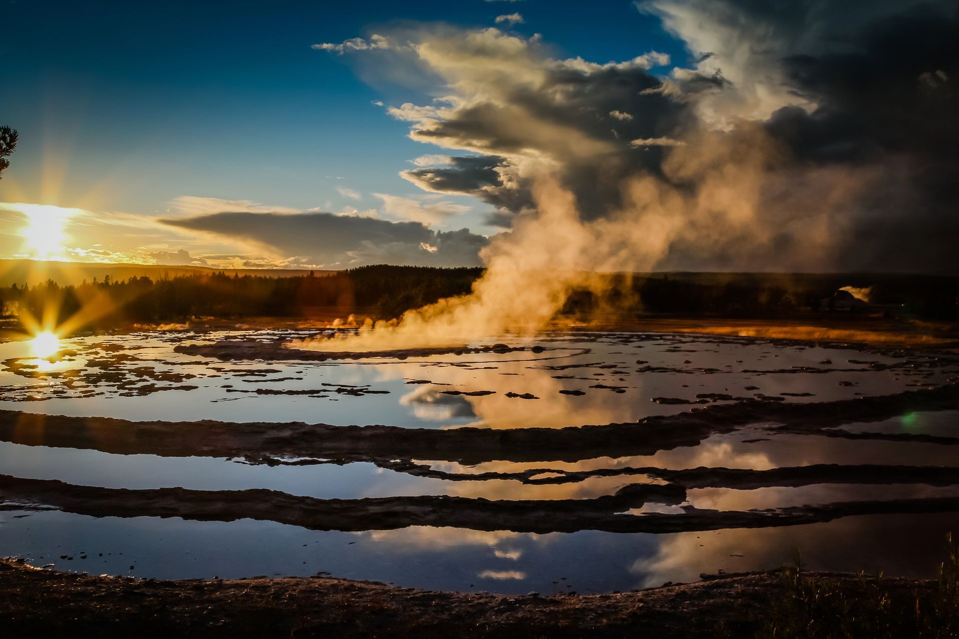 The setting sun is perfectly mirrored in the glass-like reflections of water that fill the Great Fountain Geyser.