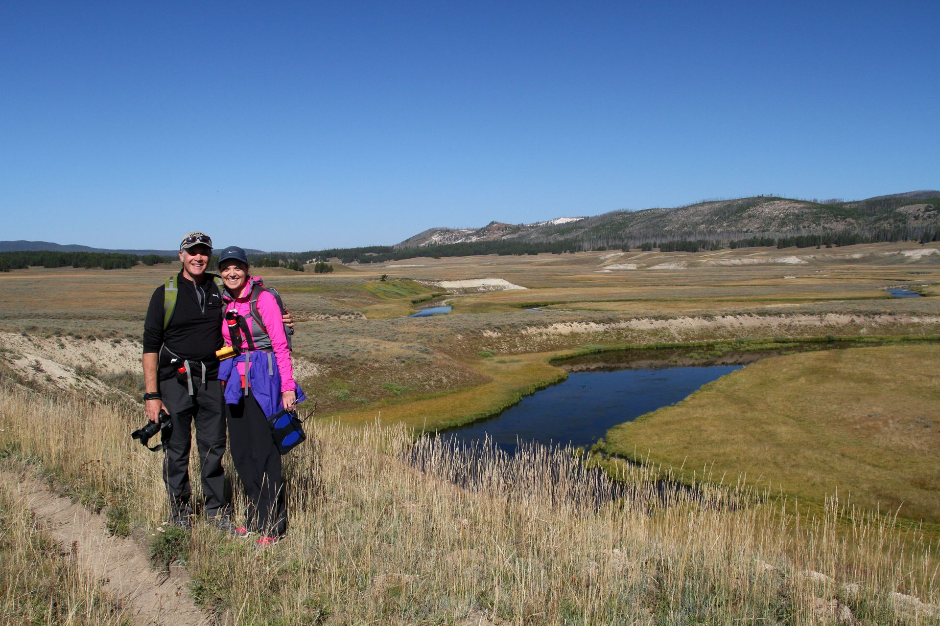 Day hikers pose for a photo beside the clear and slow moving waters of Pelican Creek.