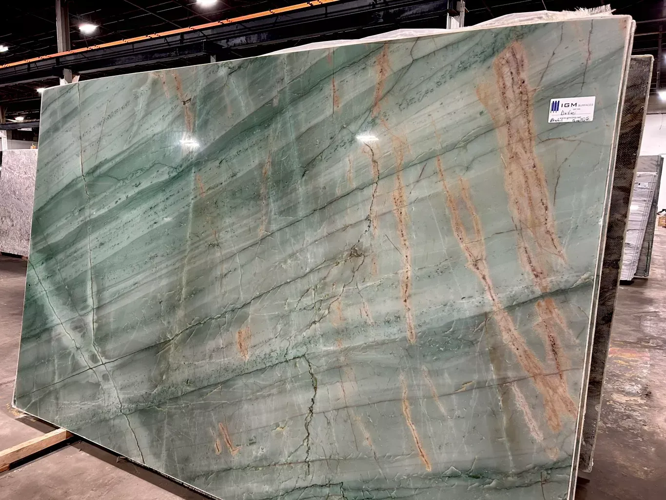 A large green marble slab is sitting on the ground in a warehouse.