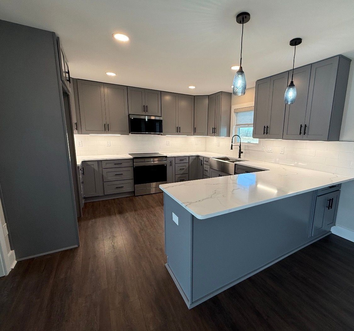 A modern kitchen with cherry wood cabinets, white and blue marble countertops, and a vibrant blue tile backsplash.