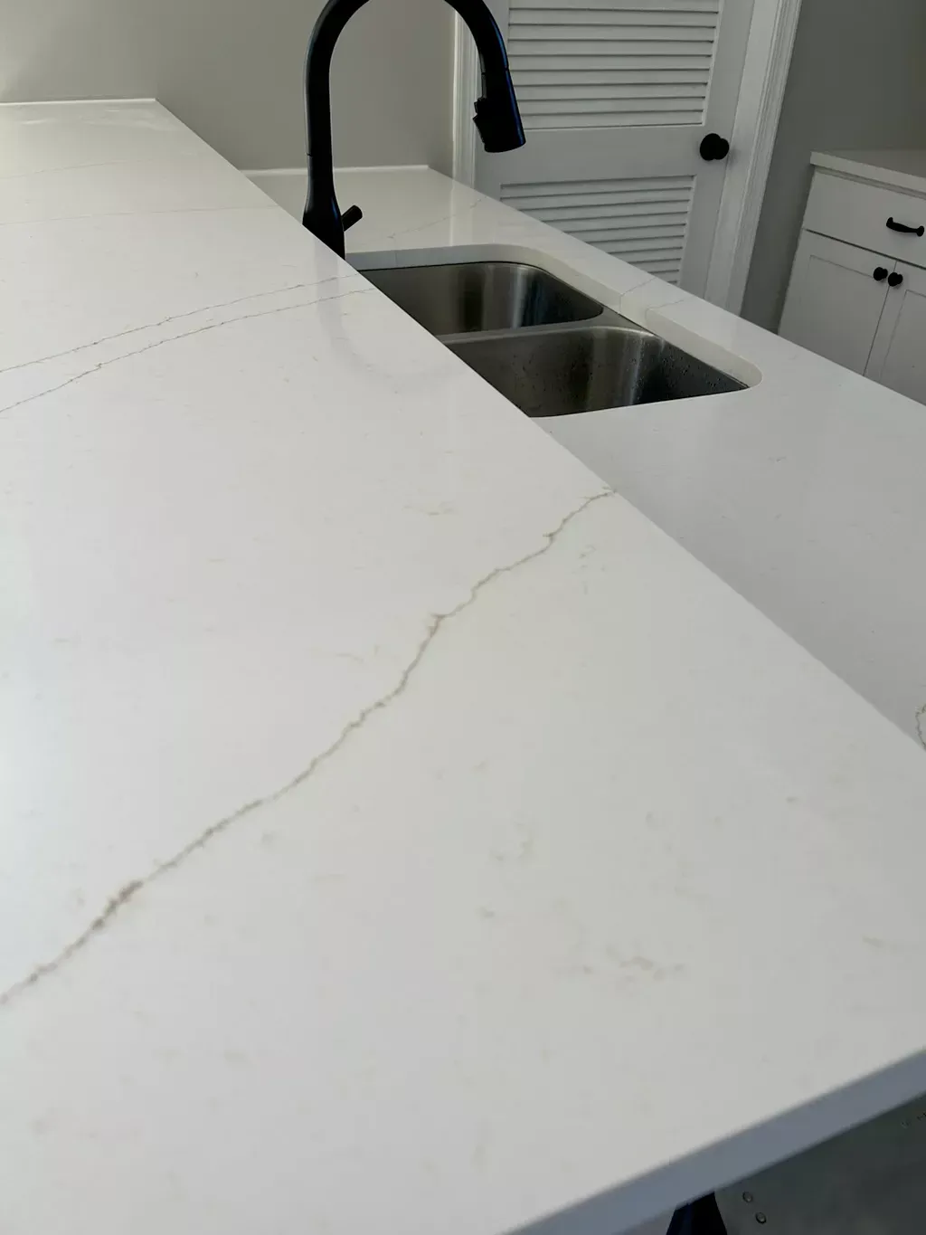 A kitchen counter with two sinks and a black faucet.
